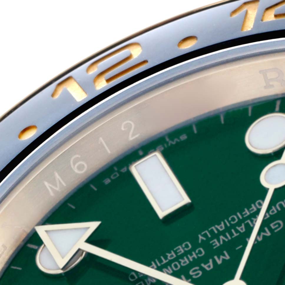 The image shows a close-up of a Rolex GMT-Master 116718 Men's Yellow Gold Green Dial's bezel and green dial with an arrow-tip GMT hand and hour markers.