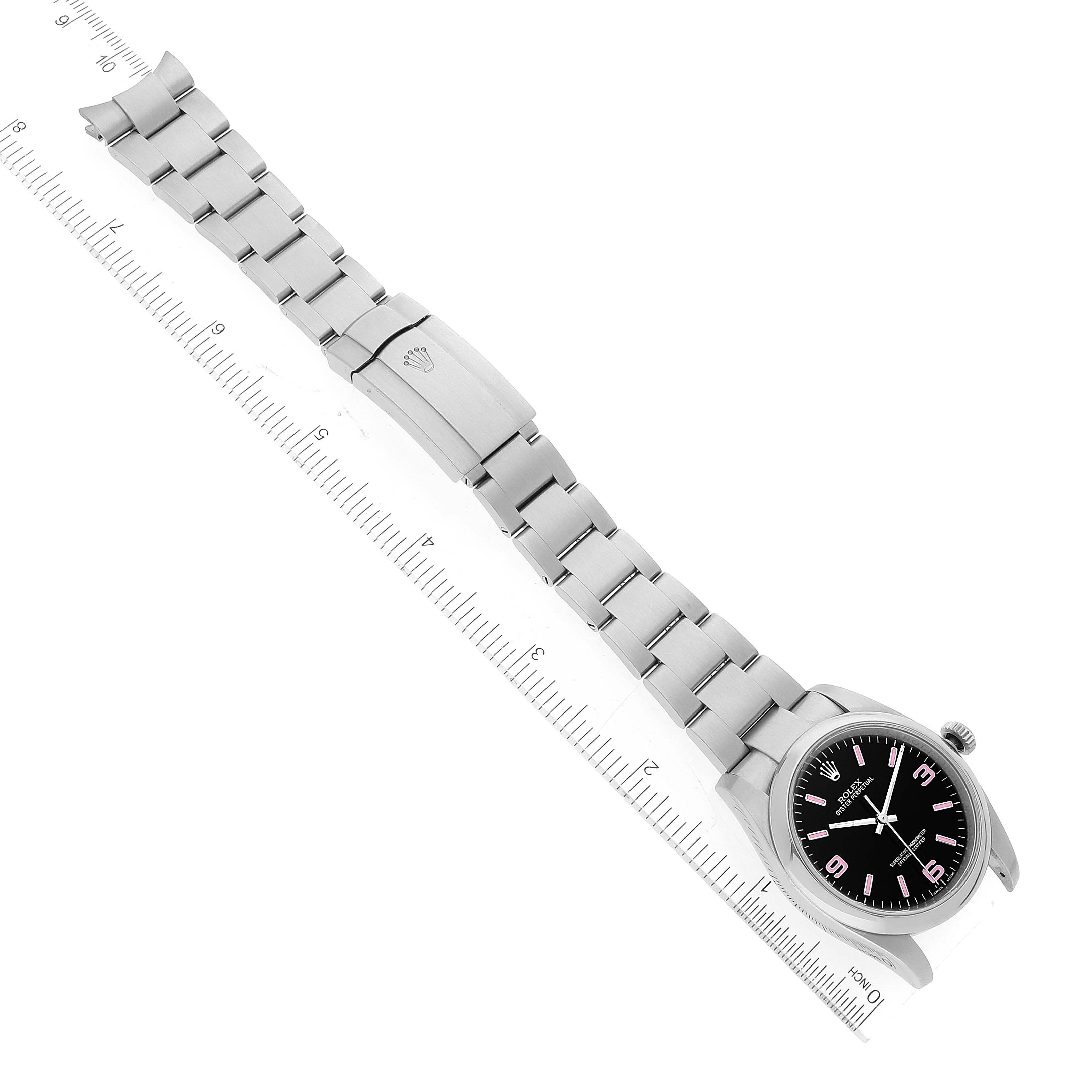 This image shows a top-down view of a Rolex Oyster Perpetual 116000 Men
s Stainless Steel Black Dial 116000 Men
s Stainless Steel Black Dial watch, including its full metal bracelet and clasp, alongside a ruler for scale.