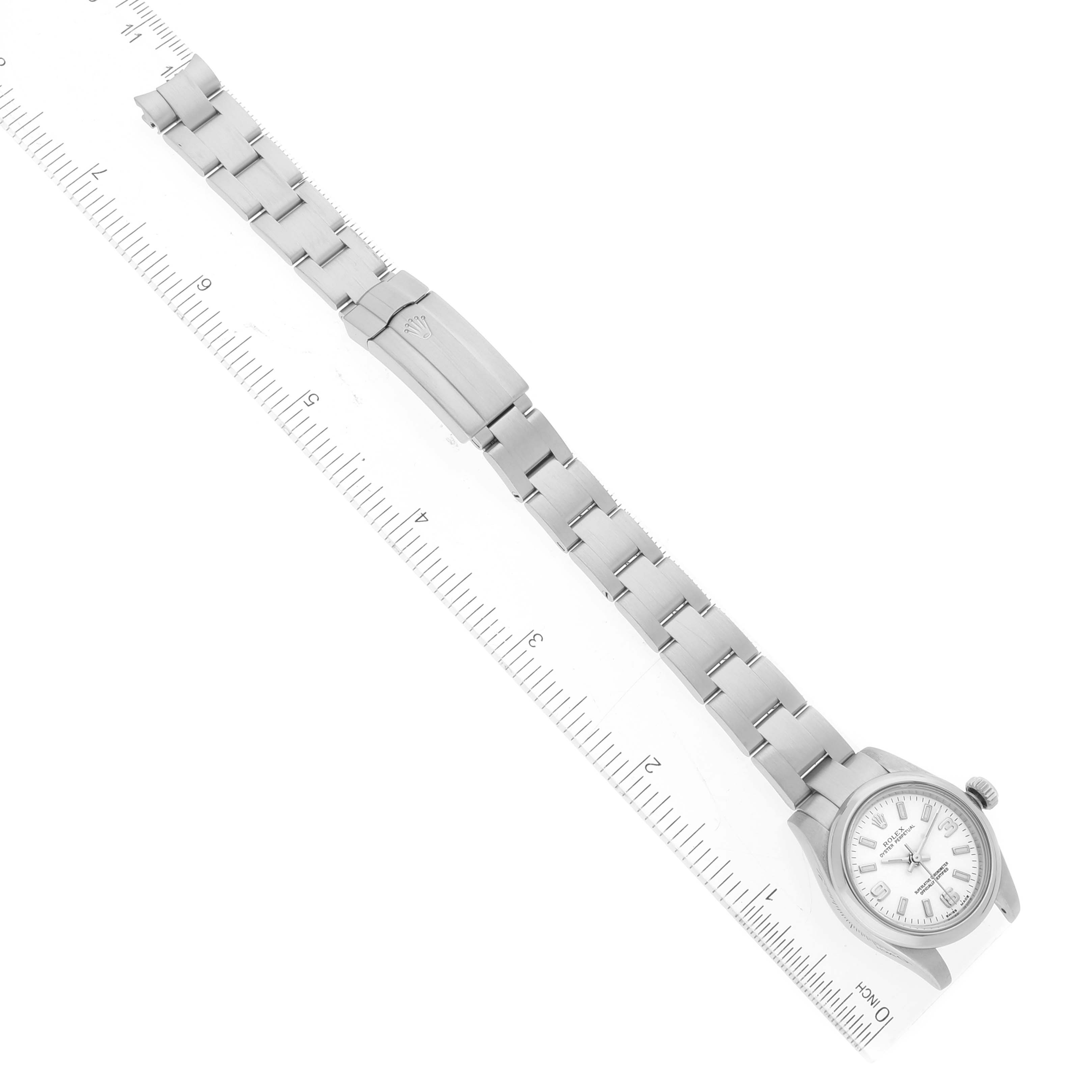 The image shows a Rolex Oyster Perpetual 176200 Women's Stainless Steel White Dial 176200 Women's Stainless Steel White Dial watch from an overhead angle, including the watch face and metal bracelet laid out with a ruler.