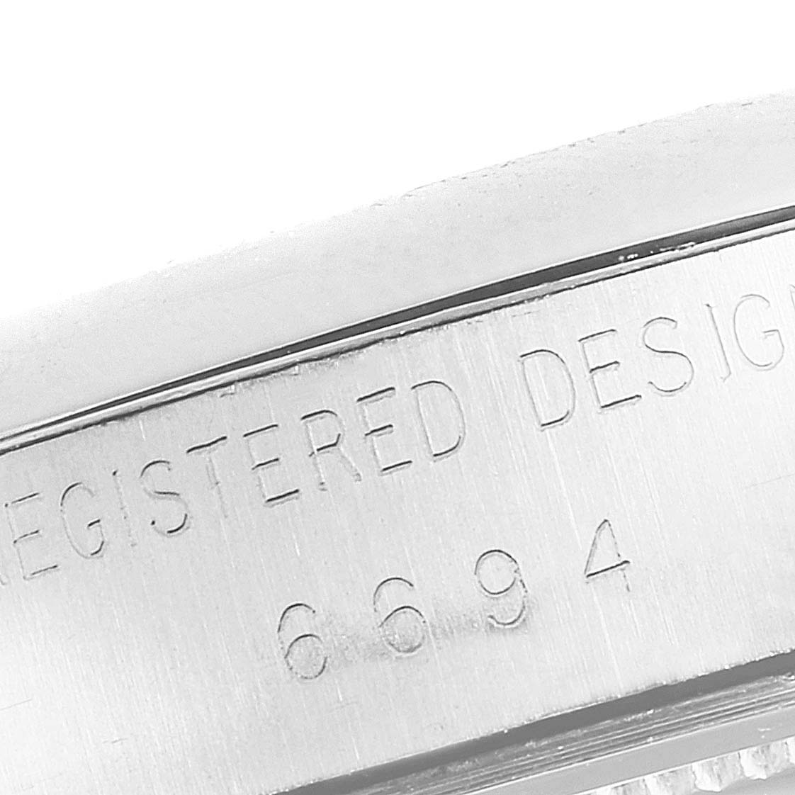 The image shows a close-up angle of the side of a Rolex Vintage Collection 6694 Men's Stainless Steel Silver Dial 6694 Men's Stainless Steel Silver Dial watch with engraved text and numbers.