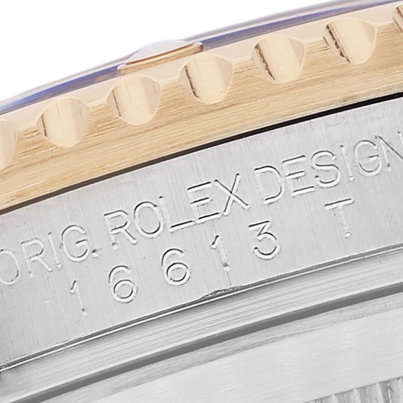 This is a macro shot showing the edge of a Rolex Submariner 16613 Men's Steel and Gold (two tone) Blue Dial 16613 Men's Steel and Gold (two tone) Blue Dial watch with engraved text and part of the bezel.