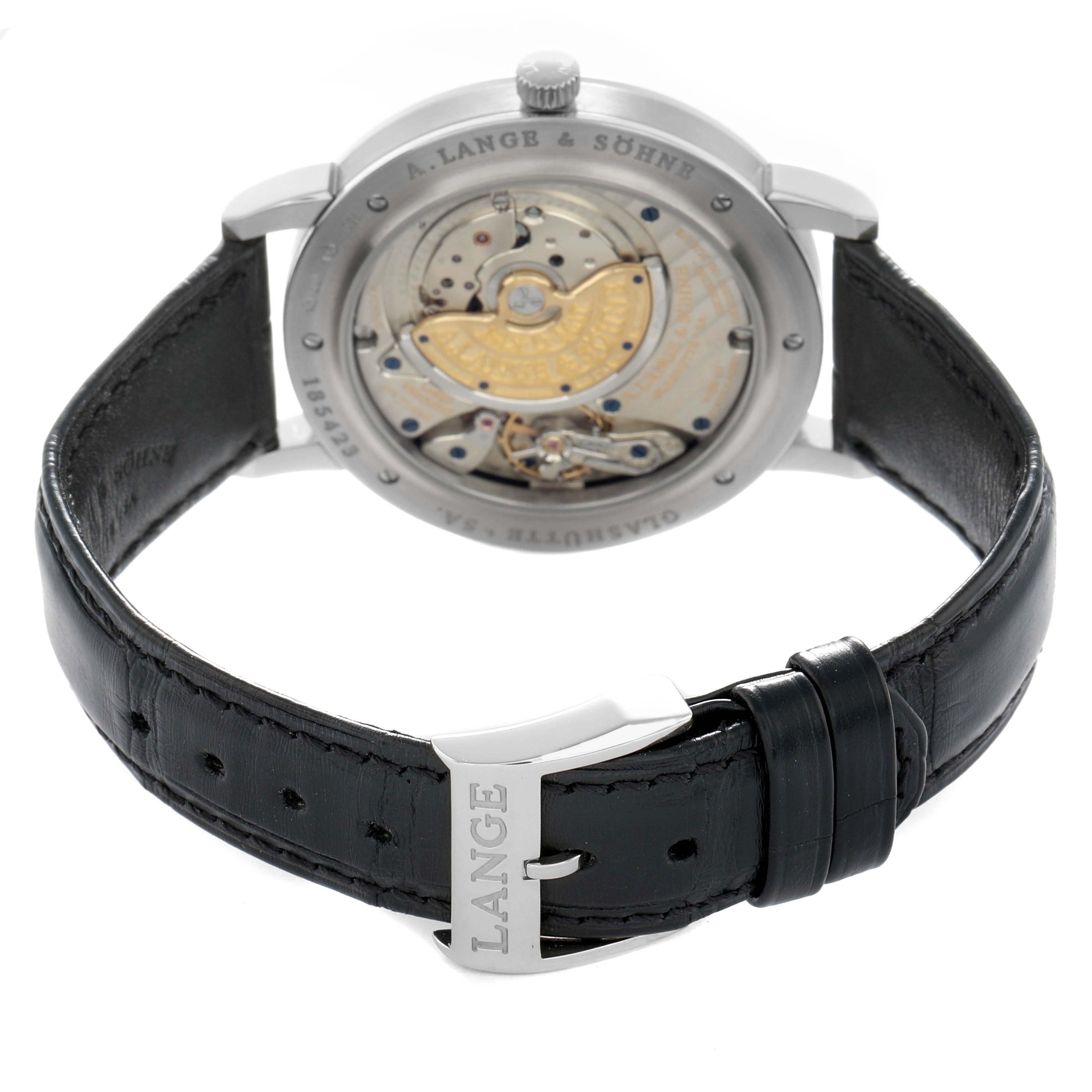 The A. Lange 
Sohne Saxonia 307.029 Men
s White Gold Black Dial watch is shown from the back, displaying its movement and black leather strap with a buckle.