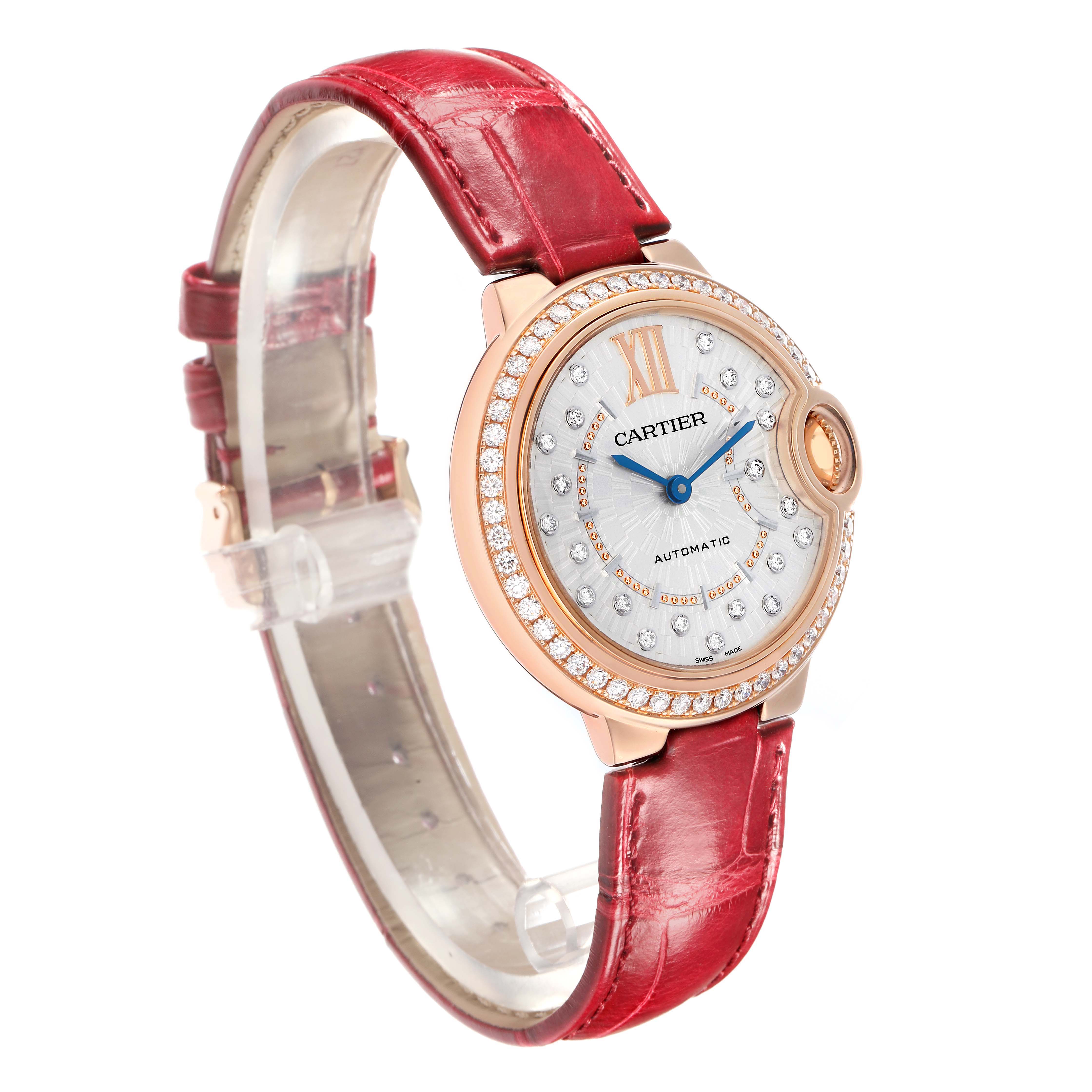The Cartier Ballon Bleu WJBB0080 Women's Rose Gold Silver Dial watch is shown at an angled view highlighting the face, red strap, and diamond-encrusted bezel.