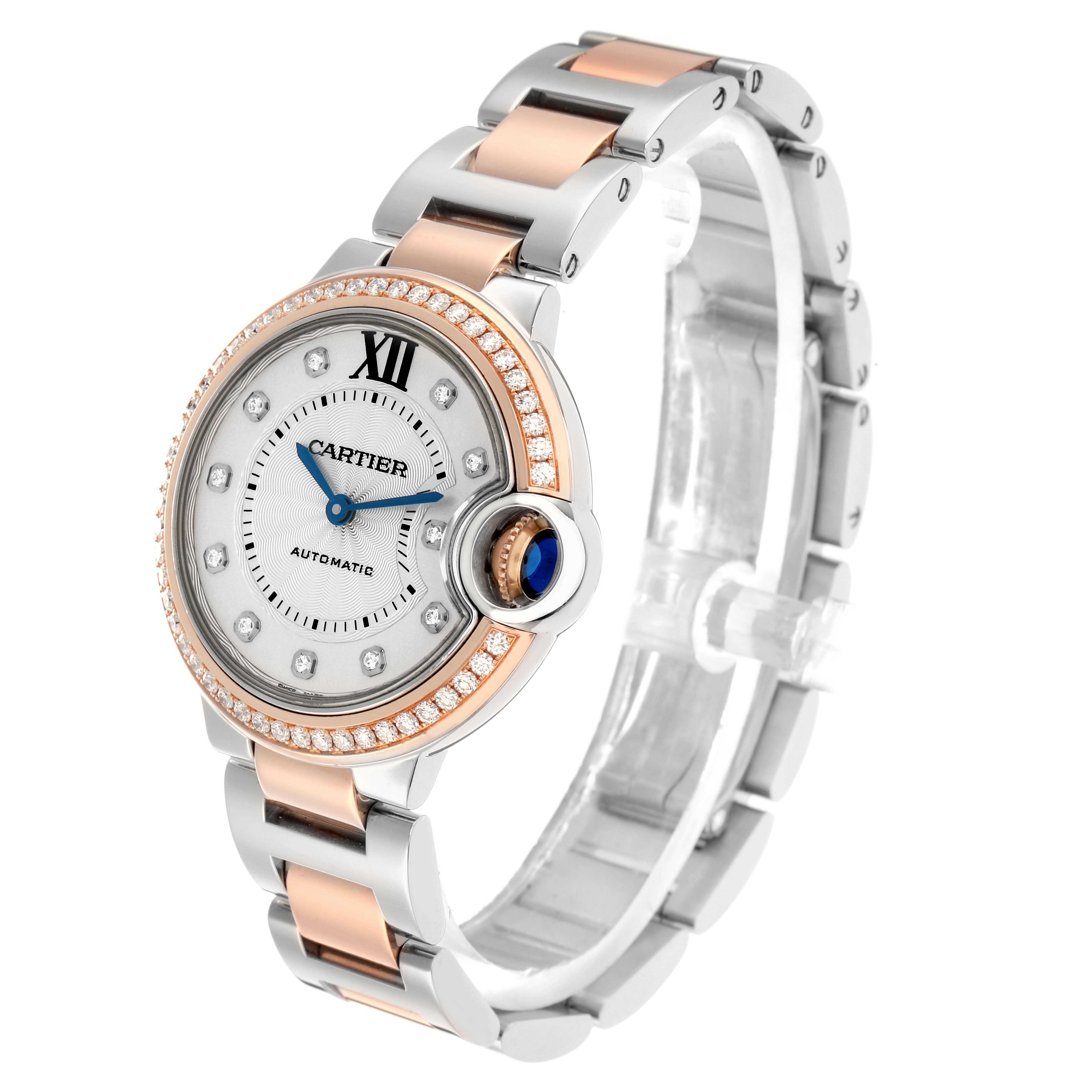 The Cartier Ballon Bleu WE902077 Women
s Steel and Gold (two tone) Silver Dial watch is shown at a three-quarter angle, highlighting its round face, blue cabochon crown, and two-tone bracelet.