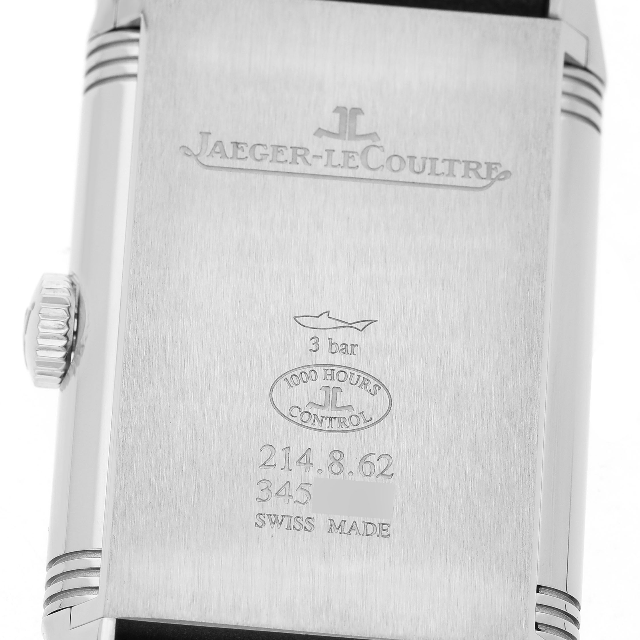 The image shows the back case of a Jaeger-LeCoultre Reverso watch, displaying engravings and the crown on the left.