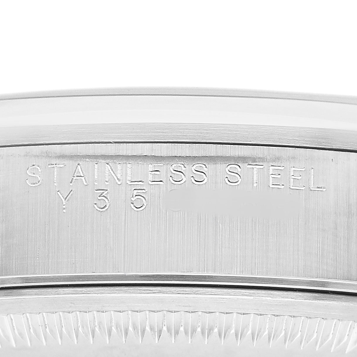 The image shows the engraved side of the case back of a Rolex Date 15200 Men's Stainless Steel Silver Dial watch, highlighting "STAINLESS STEEL" and a partial serial number.
