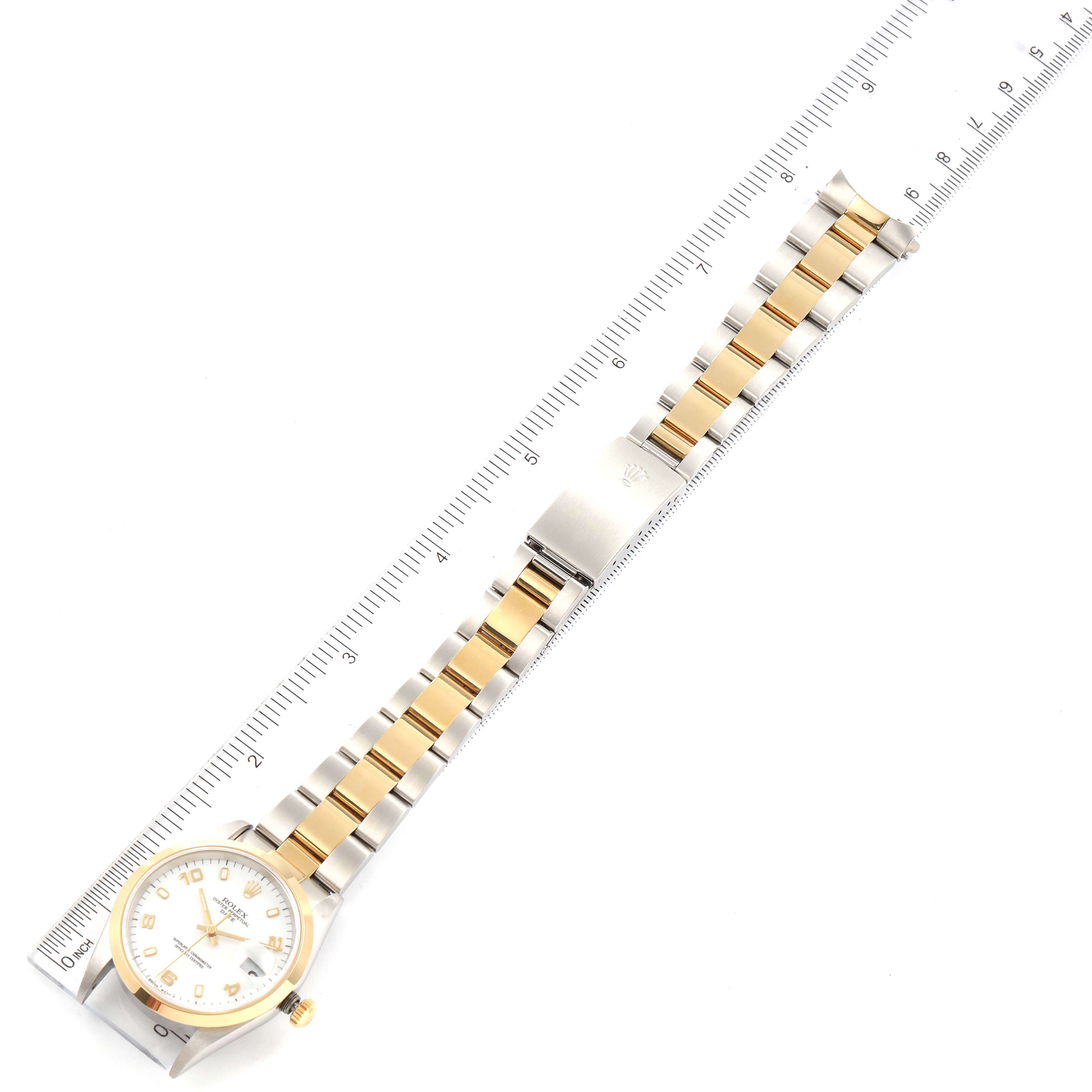 The image shows a Rolex Date 15203 Men's Steel and Gold (two tone) White Dial 15203 Men's Steel and Gold (two tone) White Dial model watch laid flat with a focus on the dial, bracelet, and clasp, against a measuring scale.