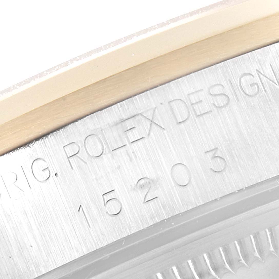 This close-up image shows the engraved model number and part of the bezel of a Rolex Date 15203 Men's Steel and Gold (two tone) White Dial 15203 Men's Steel and Gold (two tone) White Dial watch.
