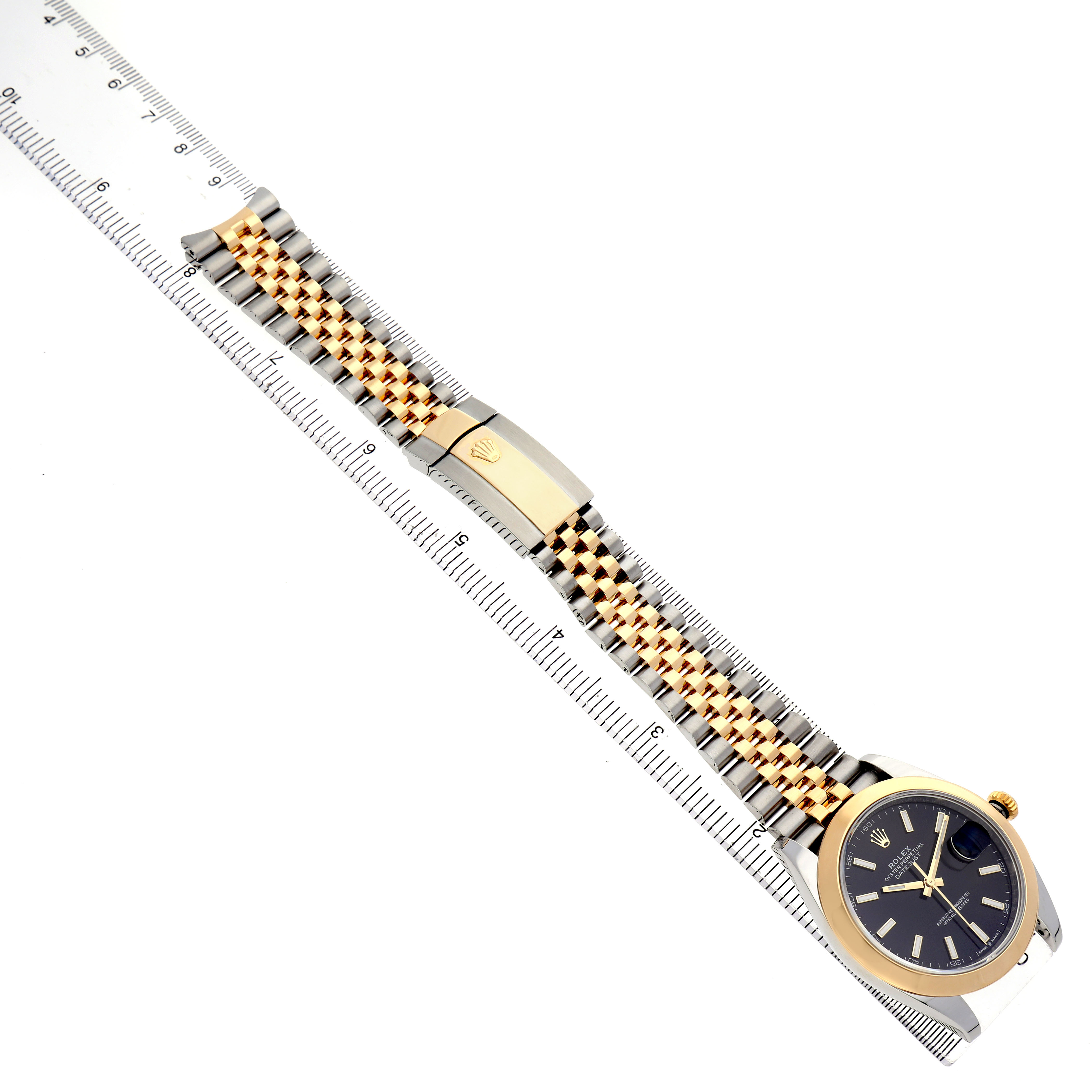 The Rolex Datejust 126303 Men's Steel and Gold (two tone) Black Dial watch is shown from a top view, highlighting the bracelet, clasp, and face alongside a ruler for scale.