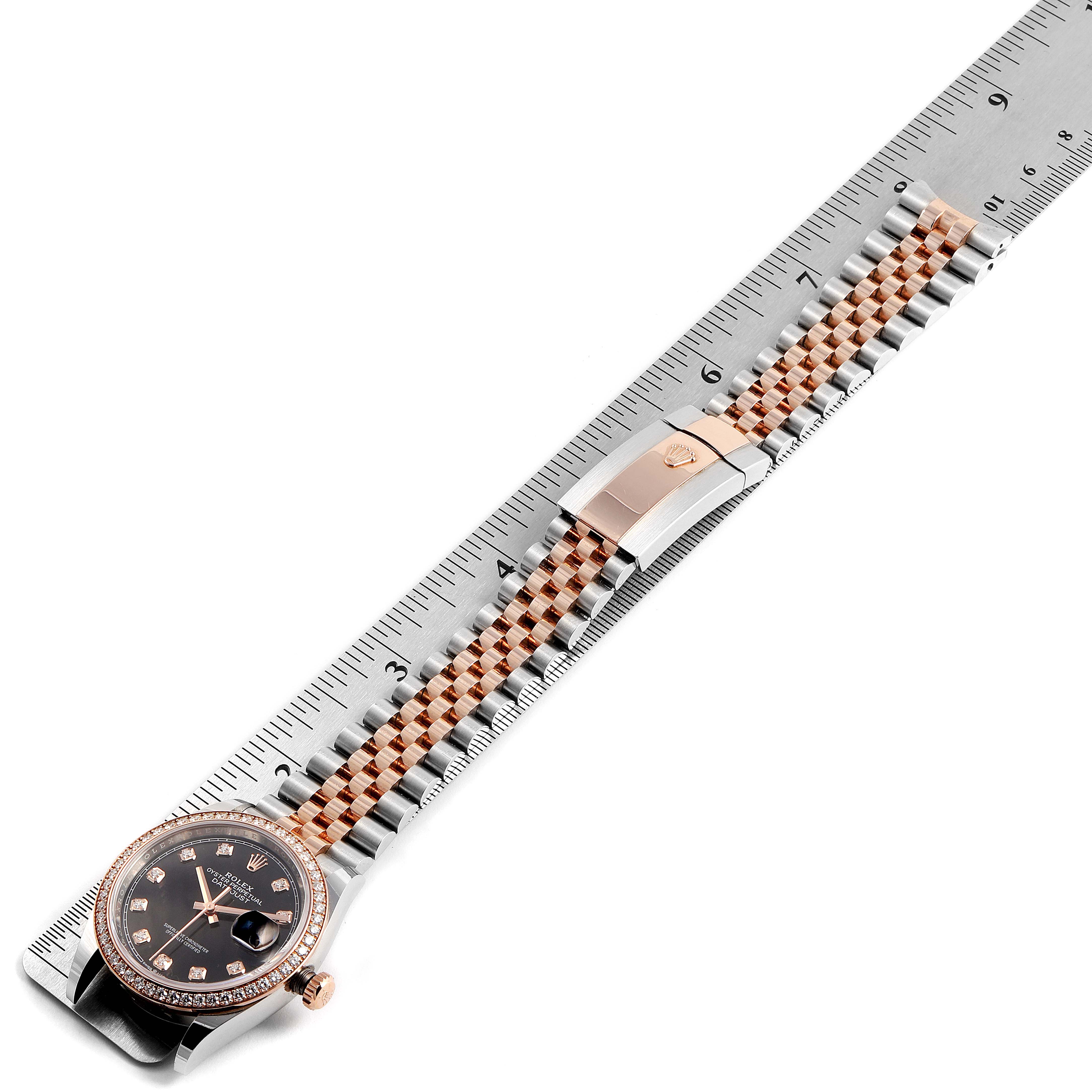 The image shows a Rolex Datejust 126281 Men's Rose Gold Black Dial 126281 Men's Rose Gold Black Dial watch from a top view, displaying its face, bezel, and jubilee bracelet placed along a ruler.