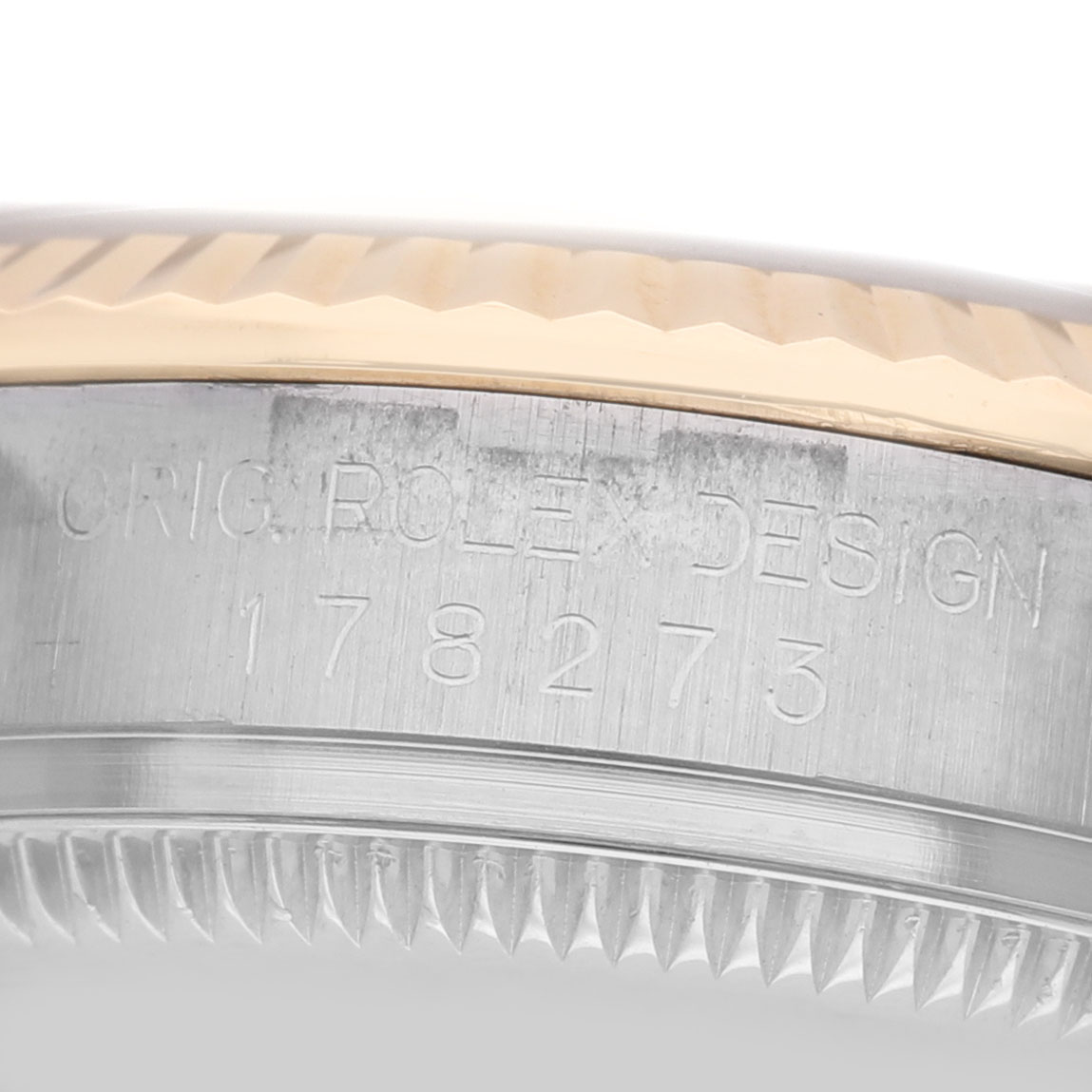 The image shows a close-up of the side of a Rolex Datejust 178273 Women's Steel and Gold (two tone) Black Dial watch case with engravings.
