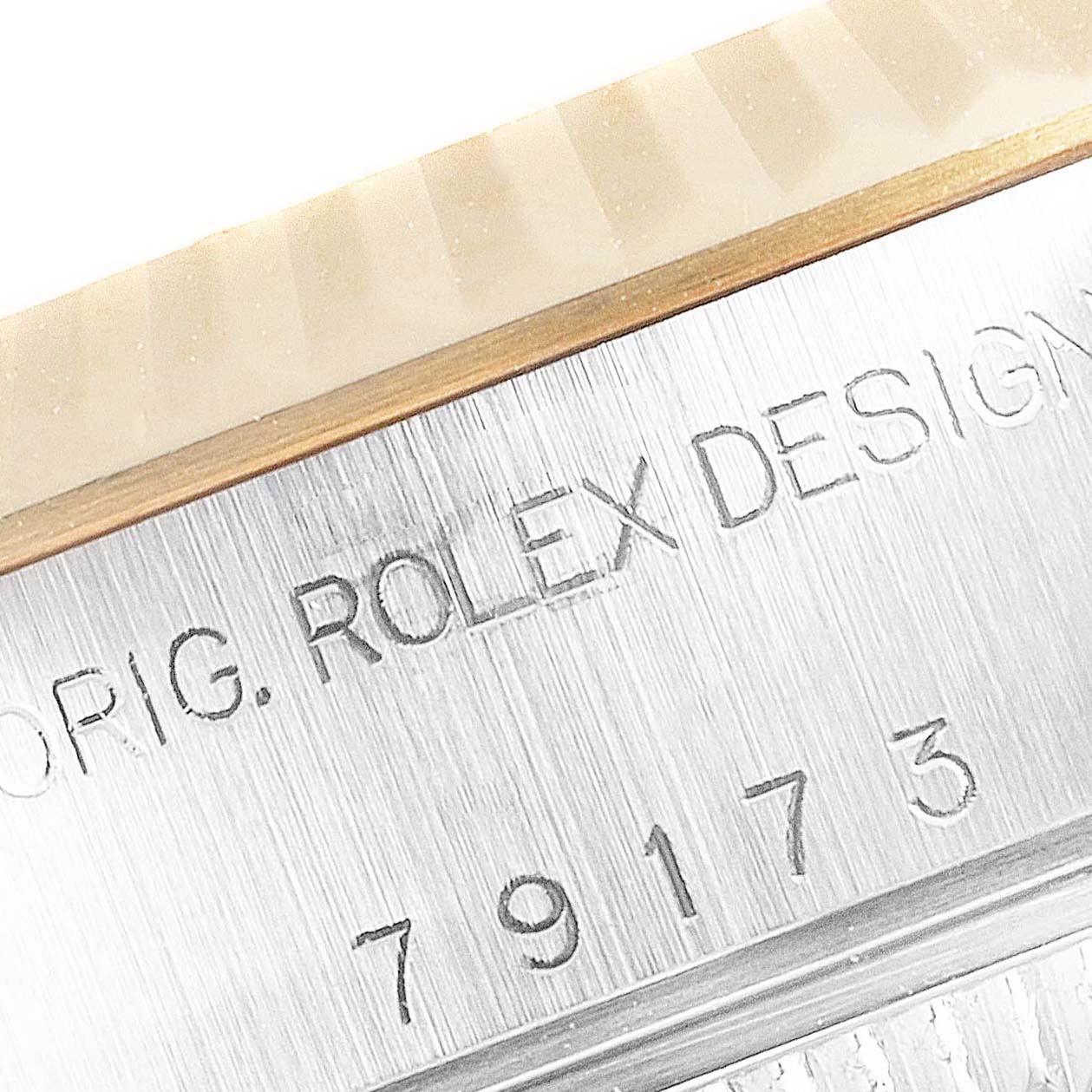 The image shows a close-up view of a Rolex Datejust 79173 Women's Steel and Gold (two tone) White Dial 79173 Women's Steel and Gold (two tone) White Dial model's bezel and engraved serial number.
