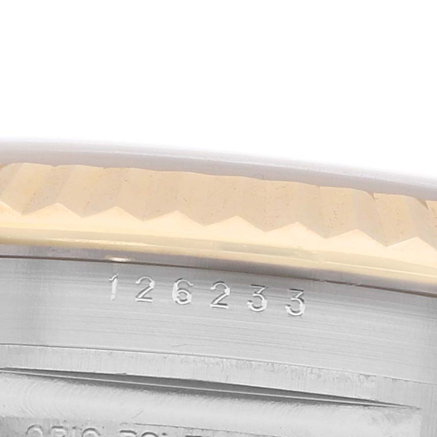 The image shows a close-up angle of the Rolex Datejust 126233 Men
s Steel and Gold (two tone) Yellow Dial
s fluted bezel and part of the case with engraved numbers.