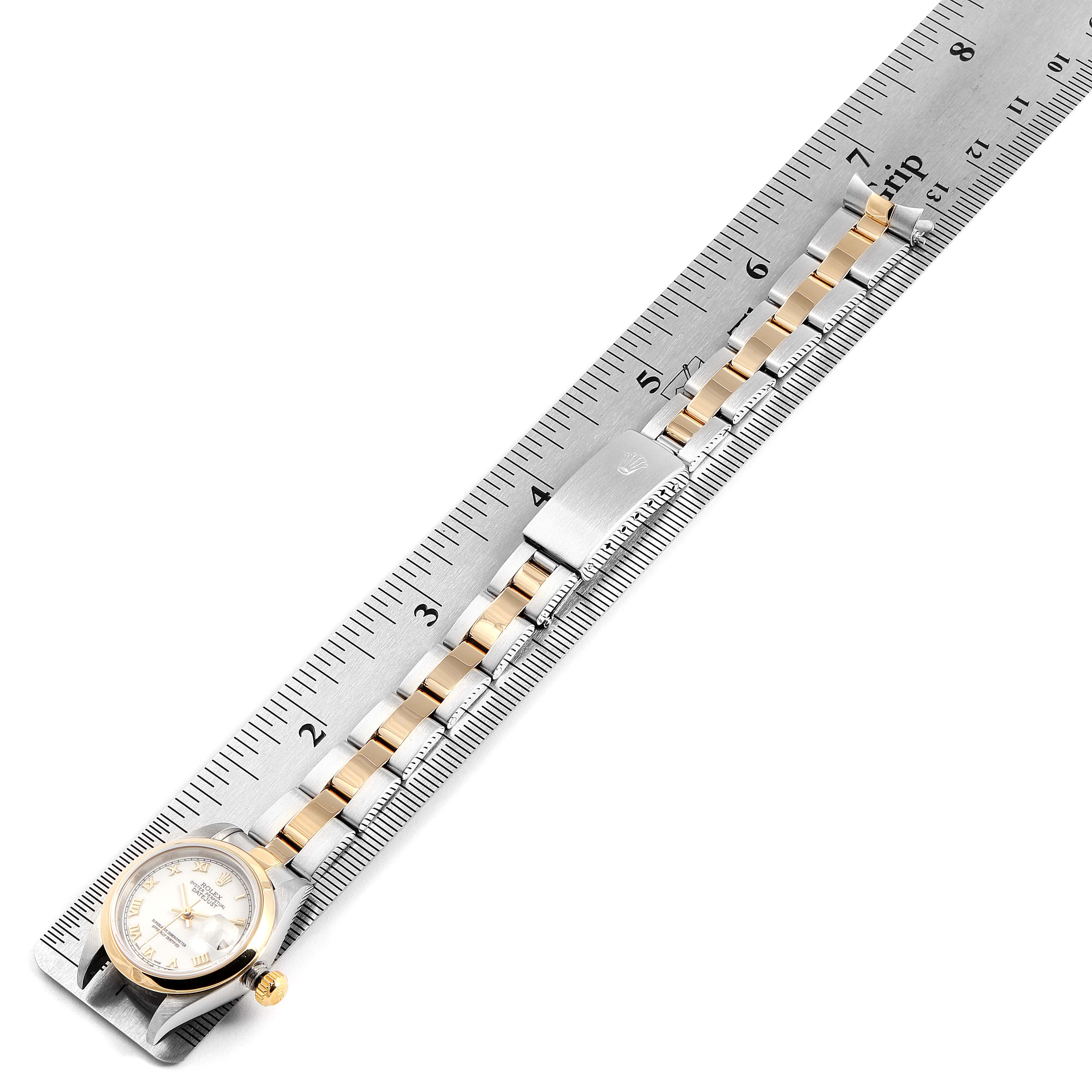 The image shows a Rolex Datejust 79163 Women's Steel and Gold (two tone) White Dial 79163 Women's Steel and Gold (two tone) White Dial watch beside a ruler, highlighting its face, crown, and band.