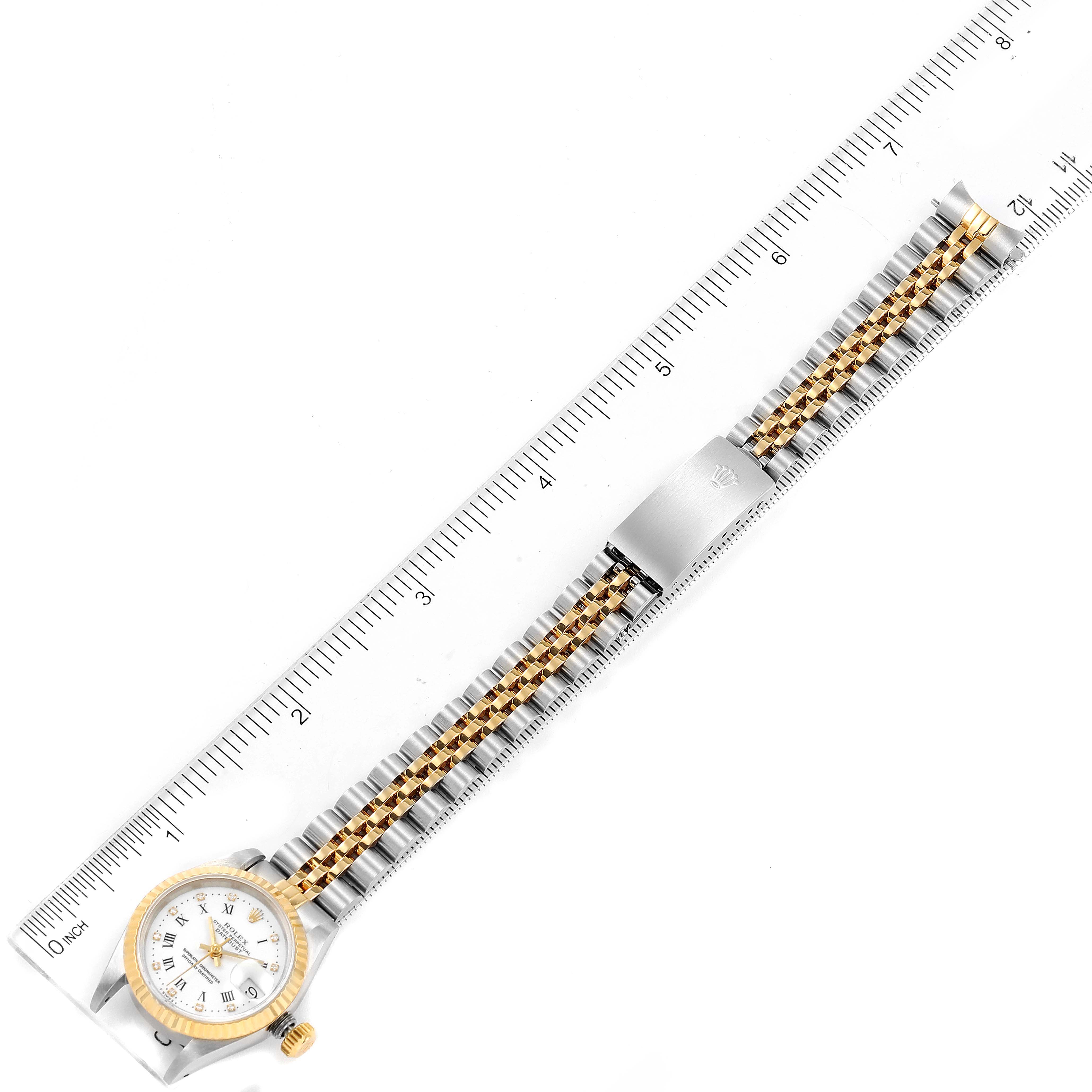 The image shows an overhead view of a Rolex Datejust 69173 Women's Steel and Gold (two tone) White Dial 69173 Women's Steel and Gold (two tone) White Dial watch with a gold and silver bracelet and a white dial, placed alongside a ruler.