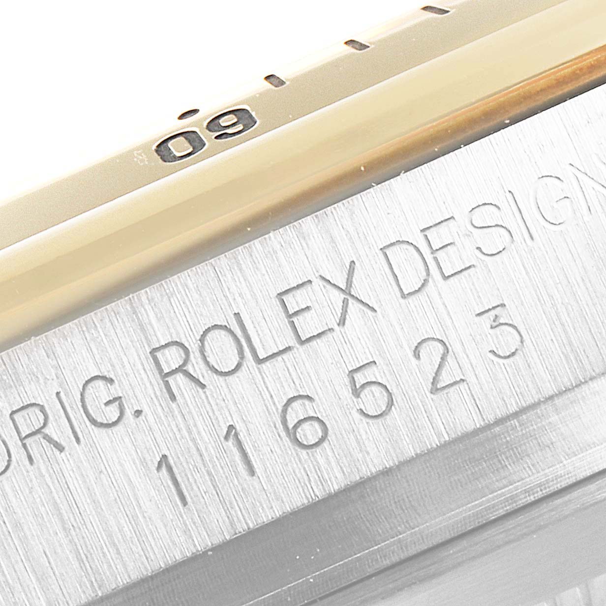 This close-up image shows the side of the Rolex Daytona 116523 Men
s Steel and Gold (two tone) Mother of Pearl Dial 116523 Men
s Steel and Gold (two tone) Mother of Pearl Dial watch, specifically focusing on the engraved serial number and part of the bezel.