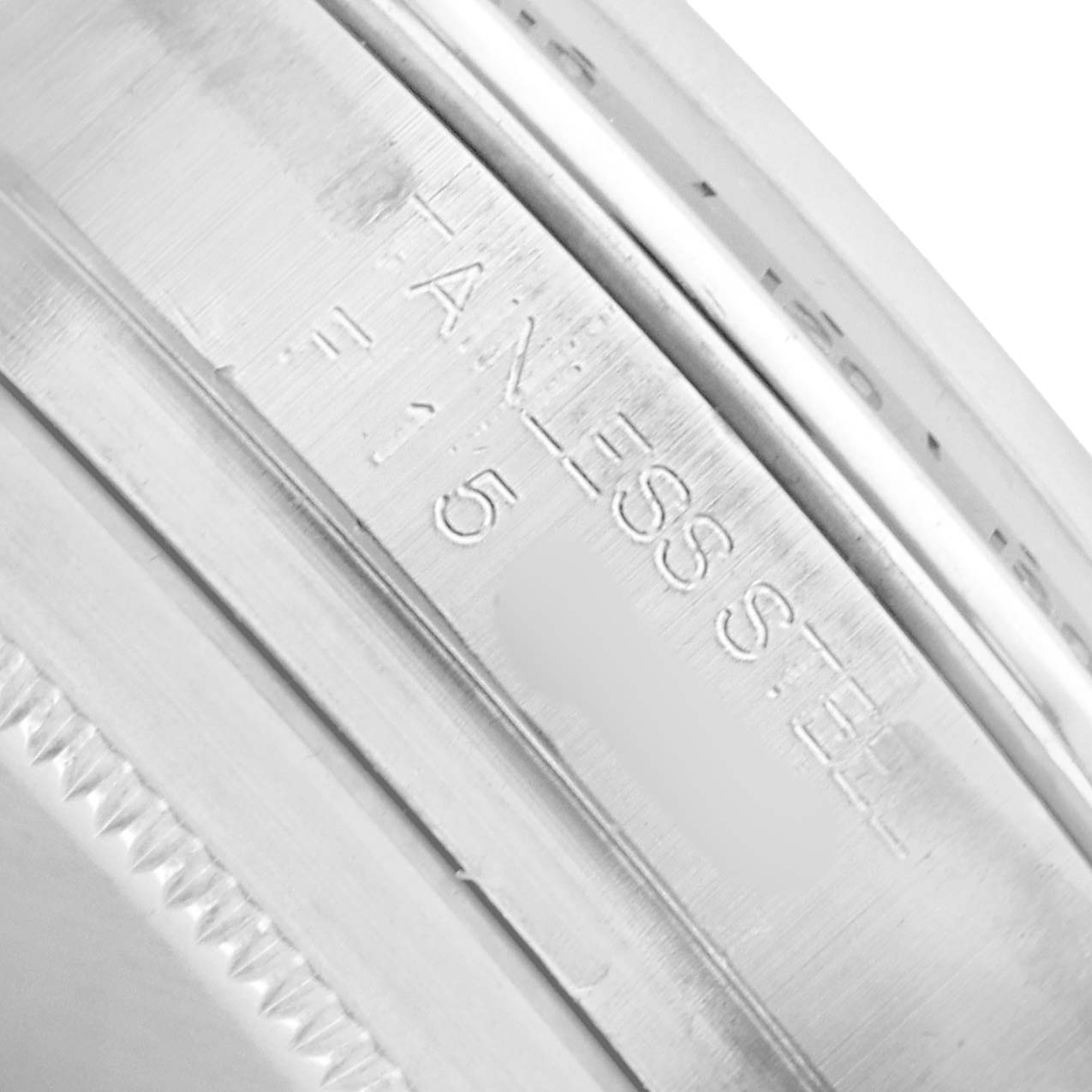 The image shows a close-up of the stainless steel case edge of a Rolex Daytona 116520 Men
s Stainless Steel White Dial watch, highlighting the engraved text.
