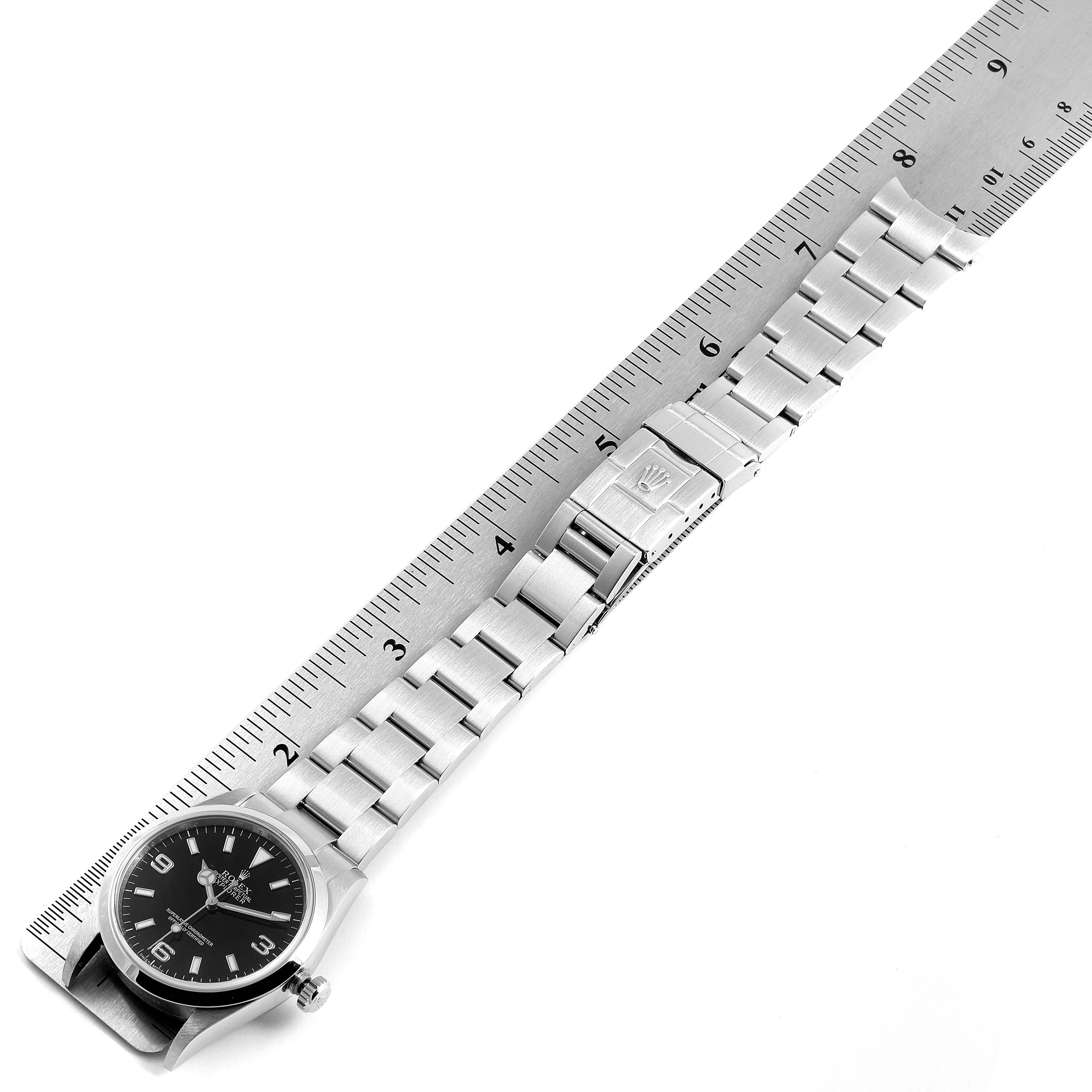 This image shows the Explorer model by Rolex with its metal bracelet and clasp laid flat against a ruler for measurement.