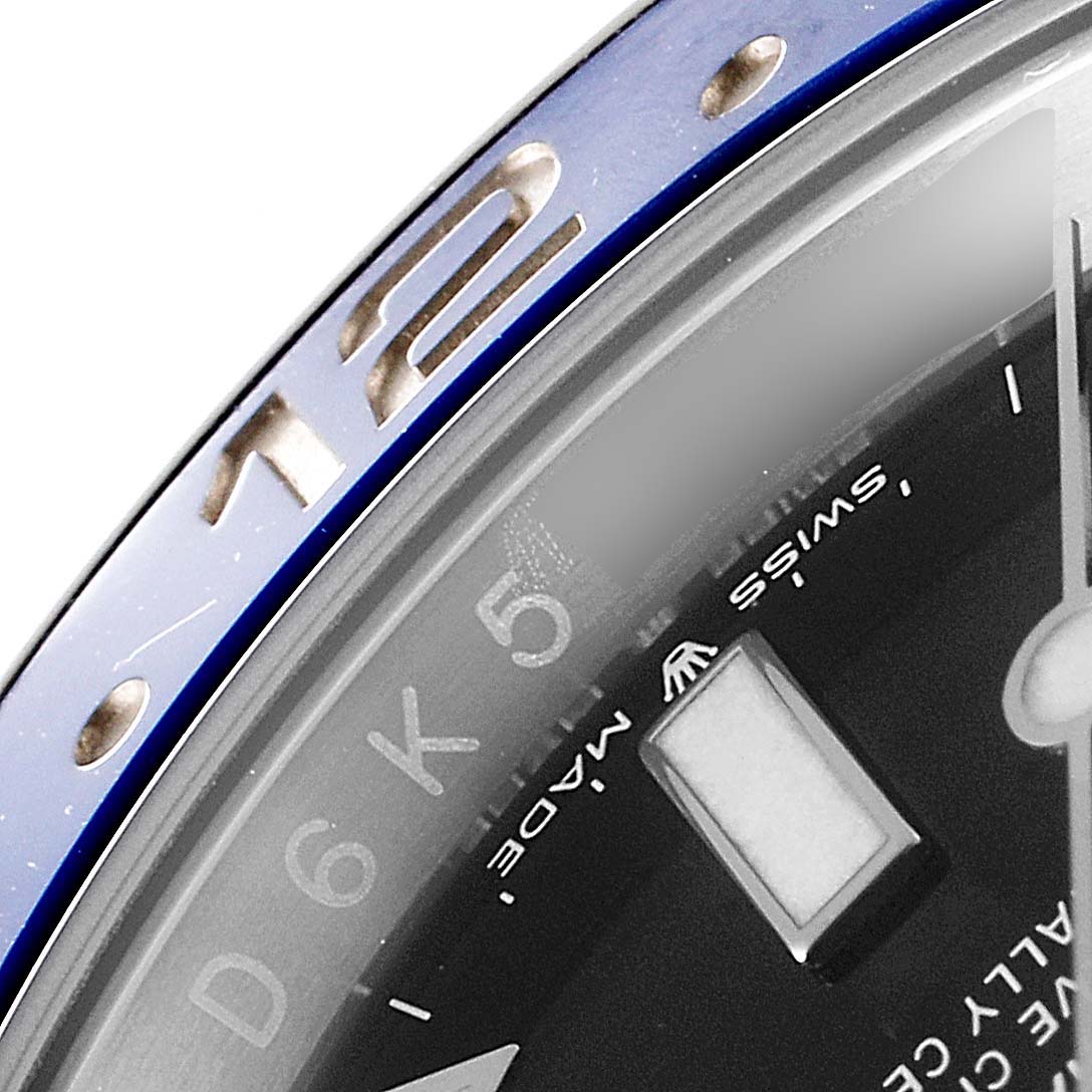 This close-up photo shows the bezel and partial dial of a Rolex GMT-Master 126710 Men
s Stainless Steel Black Dial 126710 Men
s Stainless Steel Black Dial watch, including the "12" marker and some hour indices.