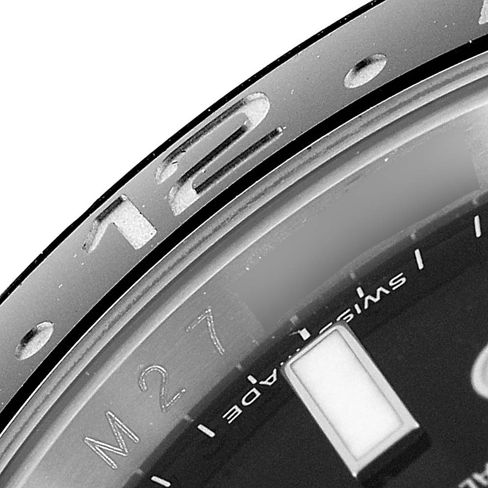 This close-up image of the Rolex GMT-Master 116710 Men
s Stainless Steel Black Dial 116710 Men
s Stainless Steel Black Dial watch shows part of the bezel, the 12-hour marker, and a portion of the dial with text.