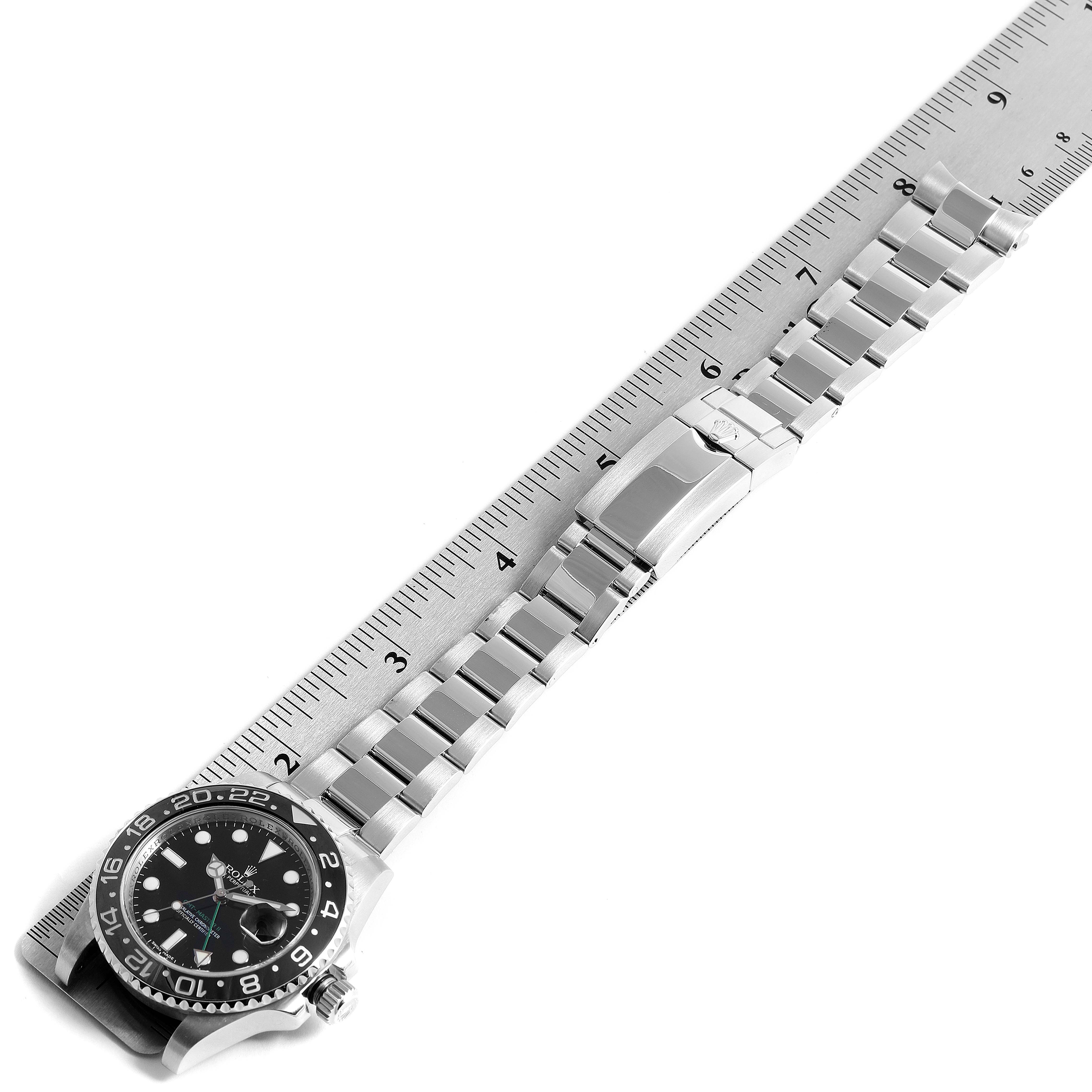 The image shows a top-down view of a Rolex GMT-Master 116710 Men's Stainless Steel Black Dial 116710 Men's Stainless Steel Black Dial watch with its stainless steel bracelet aligned next to a ruler.