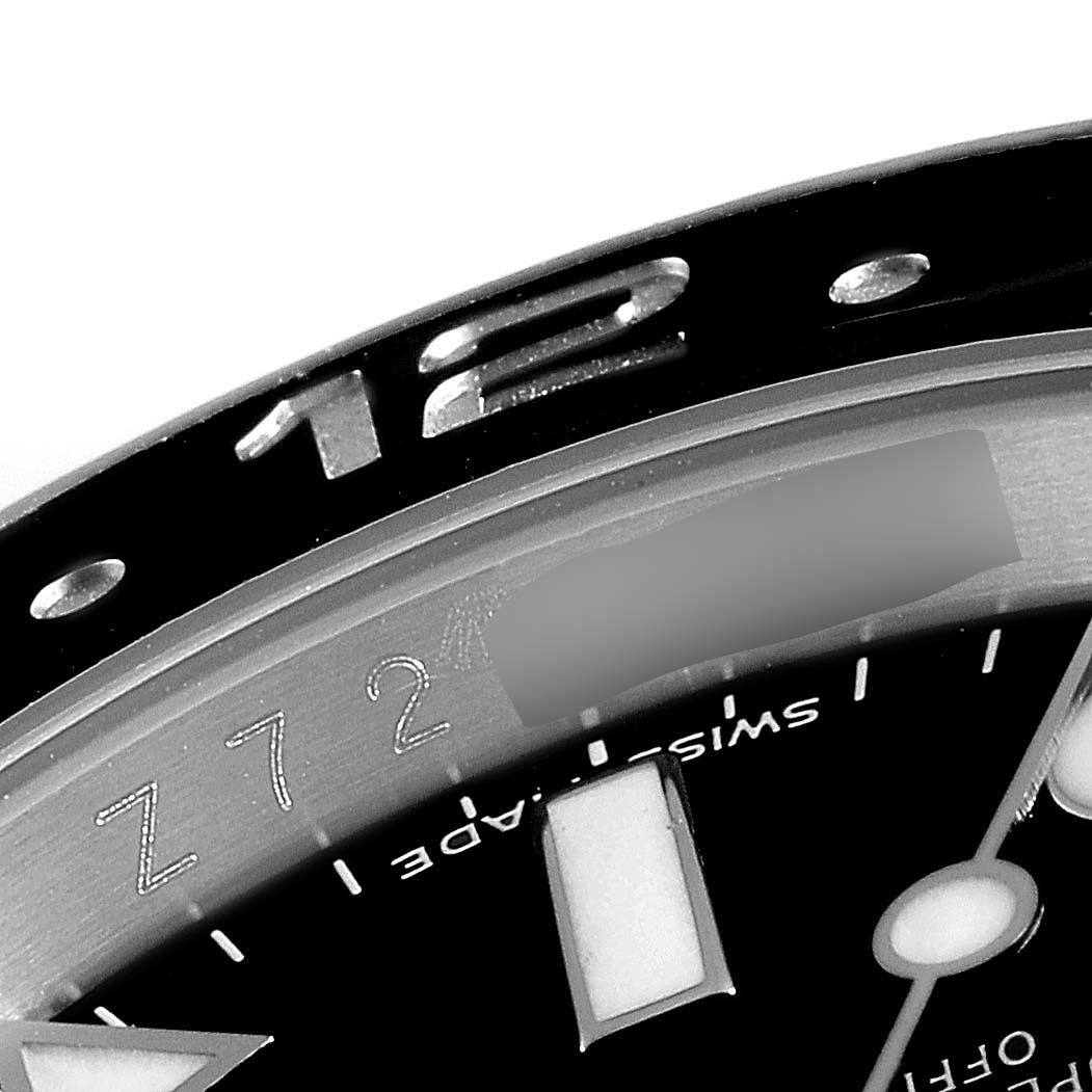 This close-up image shows part of the bezel and dial of a Rolex GMT-Master 116710 Men's Stainless Steel Black Dial 116710 Men's Stainless Steel Black Dial watch, including the "12" marker and some hour indices.