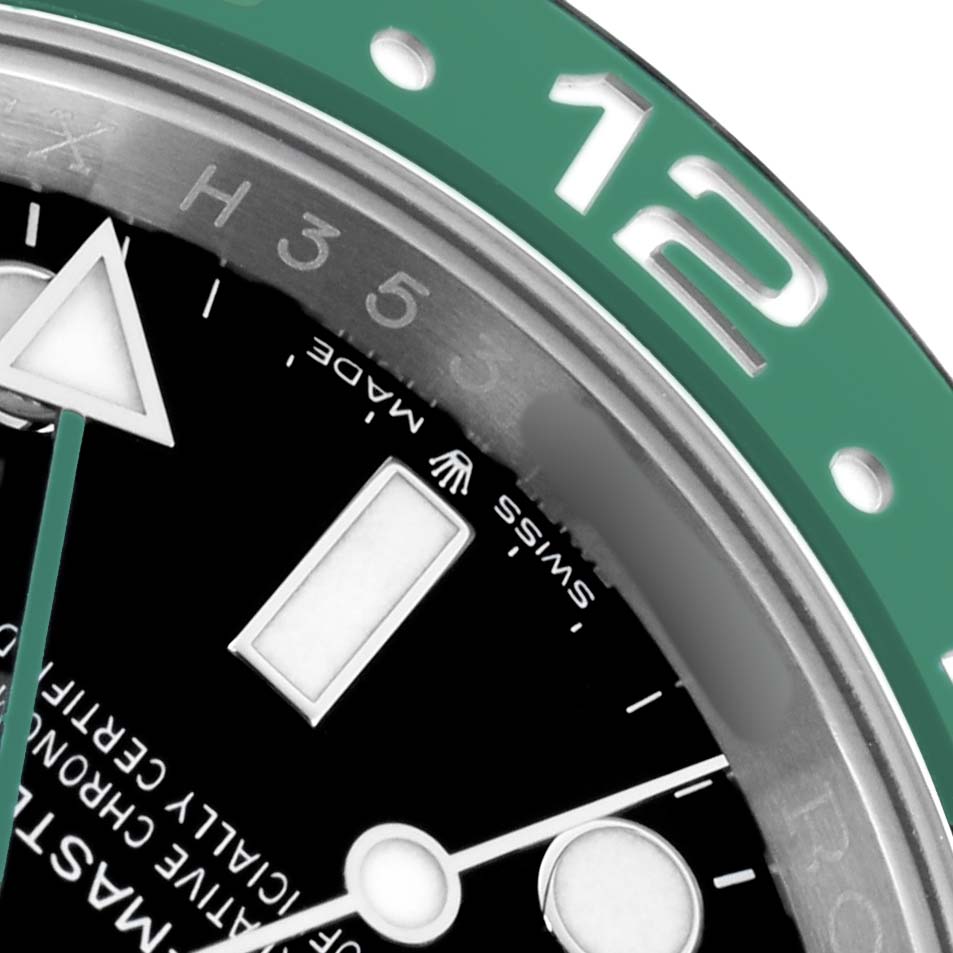 The image shows a close-up of the bezel and dial of a Rolex GMT-Master 126720 Men
s Stainless Steel Black Dial, highlighting the green bezel and part of the black dial.