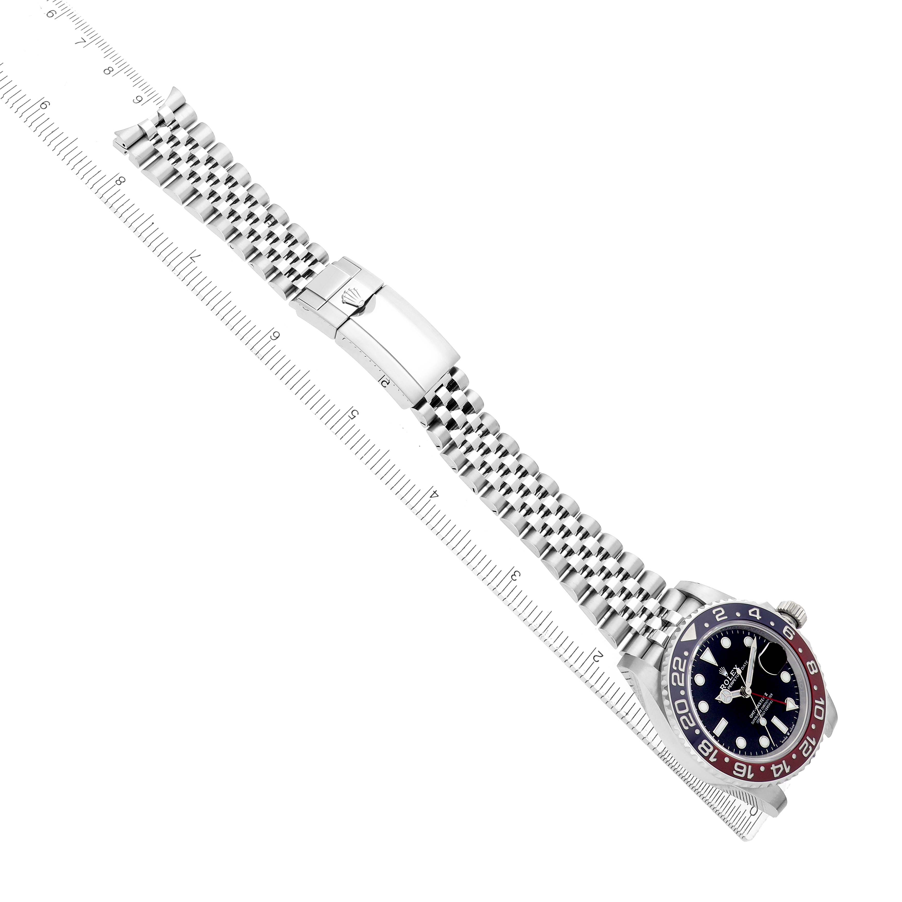 The Rolex GMT-Master 126710 Men
s Stainless Steel Black Dial watch is shown at an angle displaying the entire bracelet, clasp, and face, with a ruler for scale.