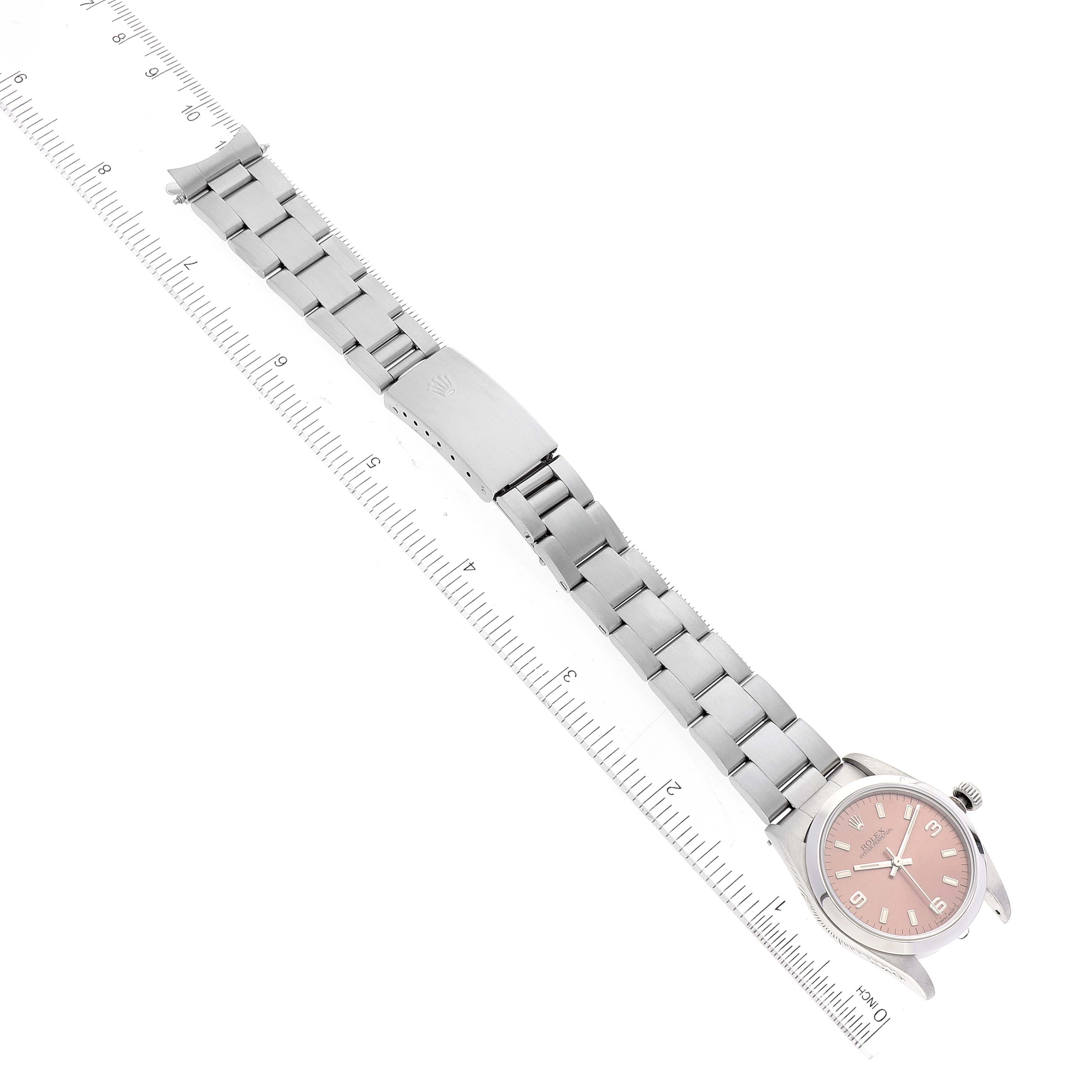 The image shows a Mid-Size Rolex watch angled diagonally, displaying the full bracelet and pink dial, alongside a measurement ruler.