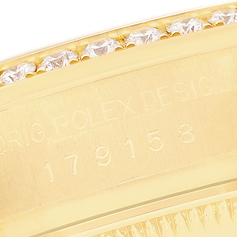 The image shows a close-up of the Rolex President 179158 Women's Yellow Gold Champagne Dial model's bezel, featuring diamonds and engraved inscriptions.