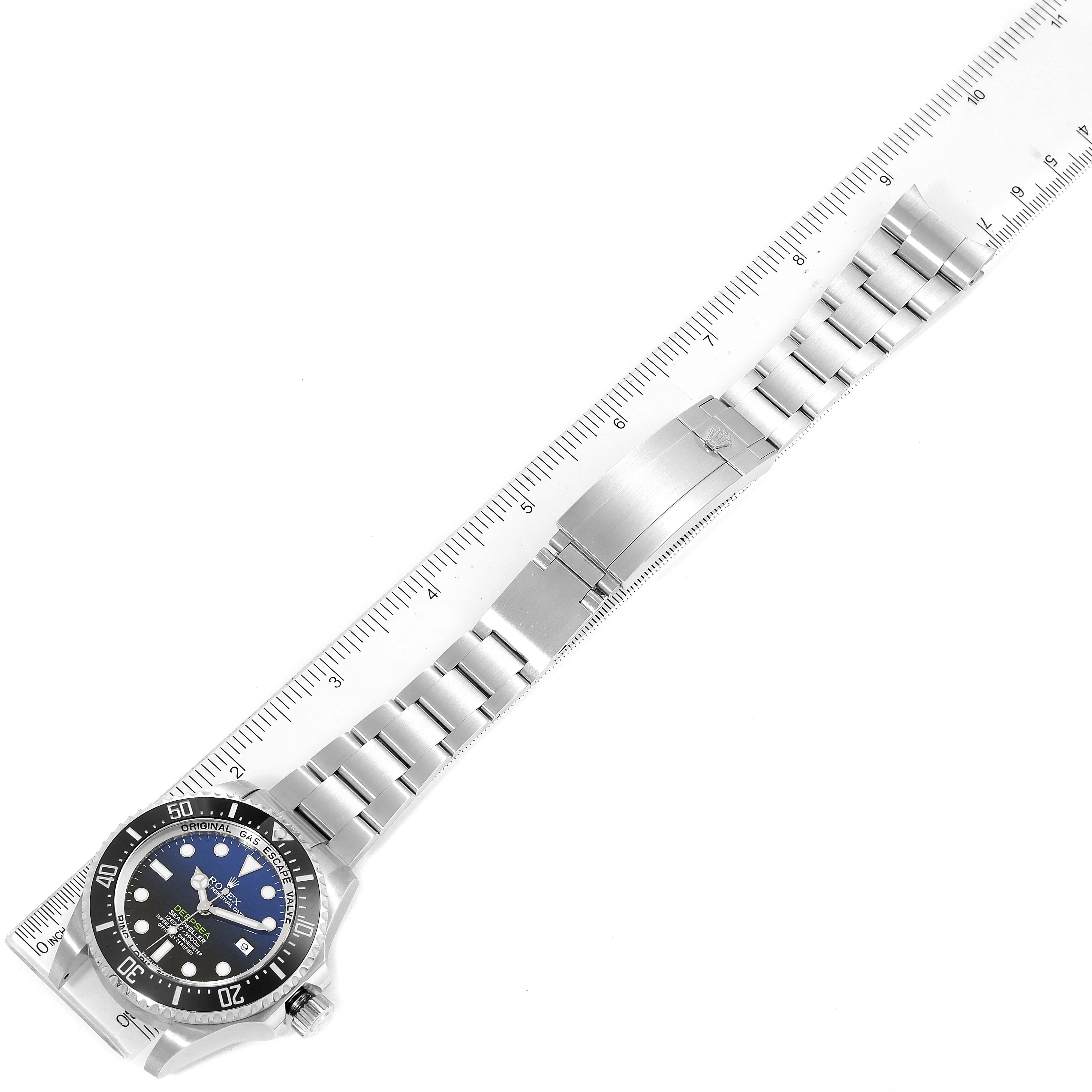 The image shows a Rolex Sea-Dweller 116660 Men
s Stainless Steel Blue Dial 116660 Men
s Stainless Steel Blue Dial watch laying flat alongside a ruler, highlighting the watch
s face and bracelet.