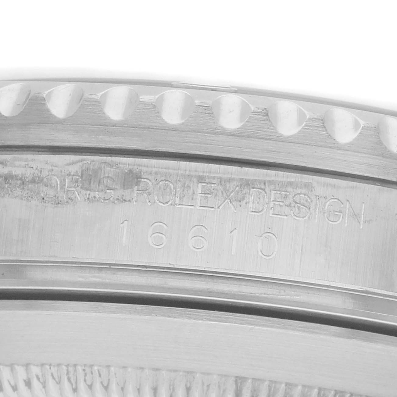 The image shows a close-up of the engraved serial number and "Rolex Design" inscription on the side of a Rolex Submariner 16610 Men
s Stainless Steel Black Dial watch case.