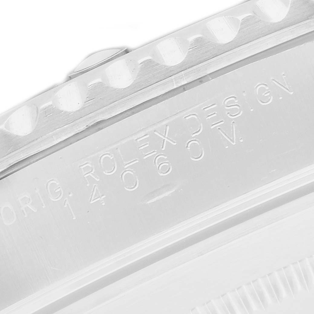 The image shows a close-up of the case side of a Rolex Submariner 14060 Men
s Stainless Steel Black Dial, focusing on the engraved text and part of the bezel.