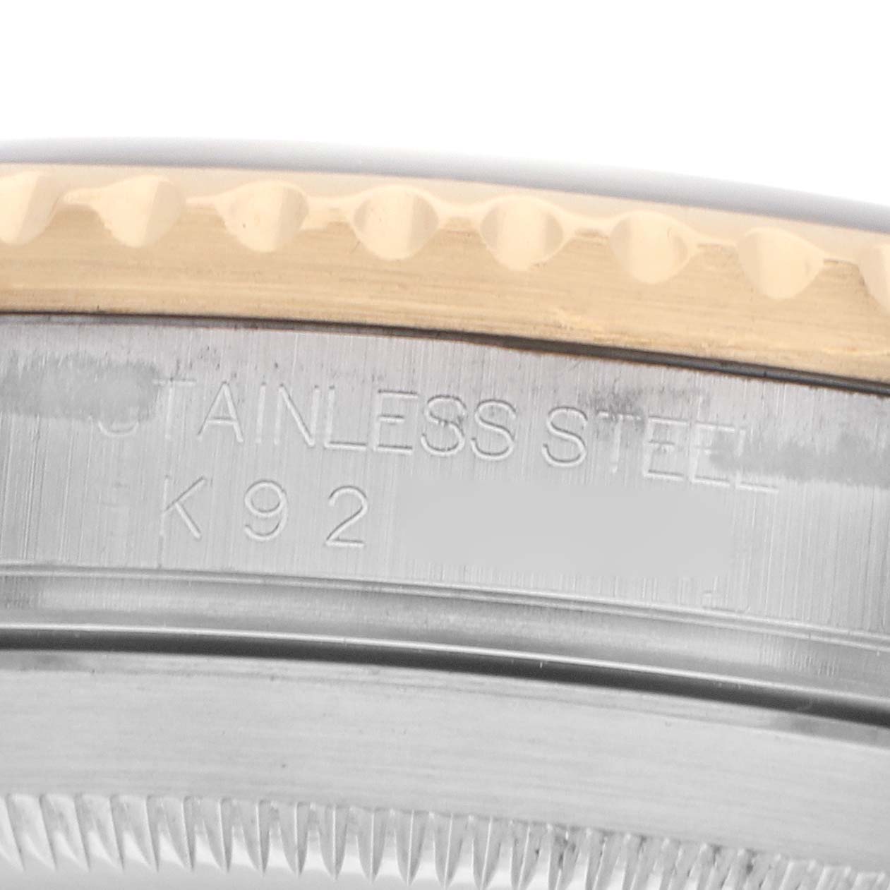 The image shows a close-up of the bezel edge and case side with "STAINLESS STEEL K92" engraved on a Rolex Submariner 16613 Men
s Steel and Gold (two tone) Black Dial.