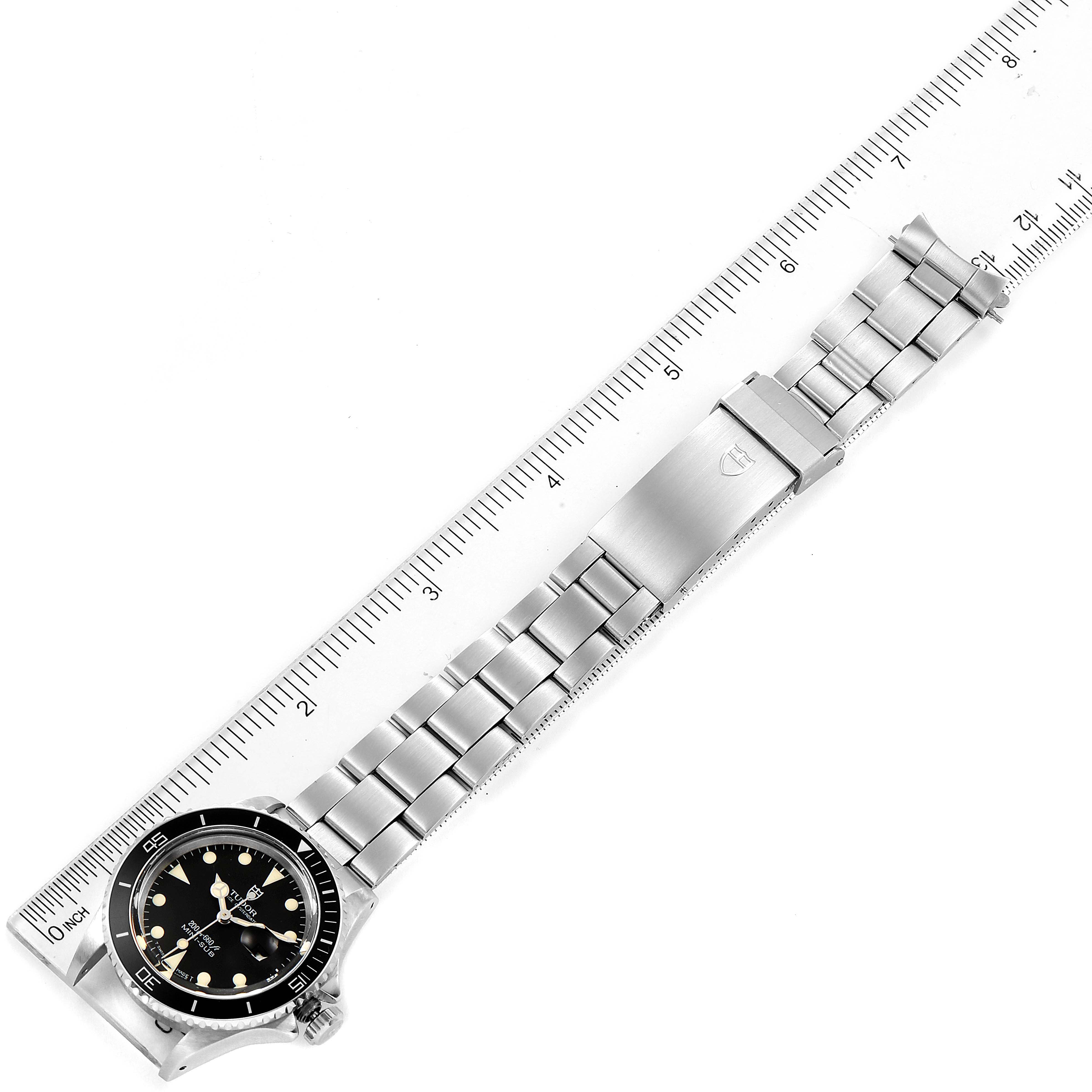 The image shows the Tudor Prince 73090 Women's Stainless Steel Black Dial 73090 Women's Stainless Steel Black Dial watch laying flat, alongside a ruler, displaying its face, bracelet, and clasp.