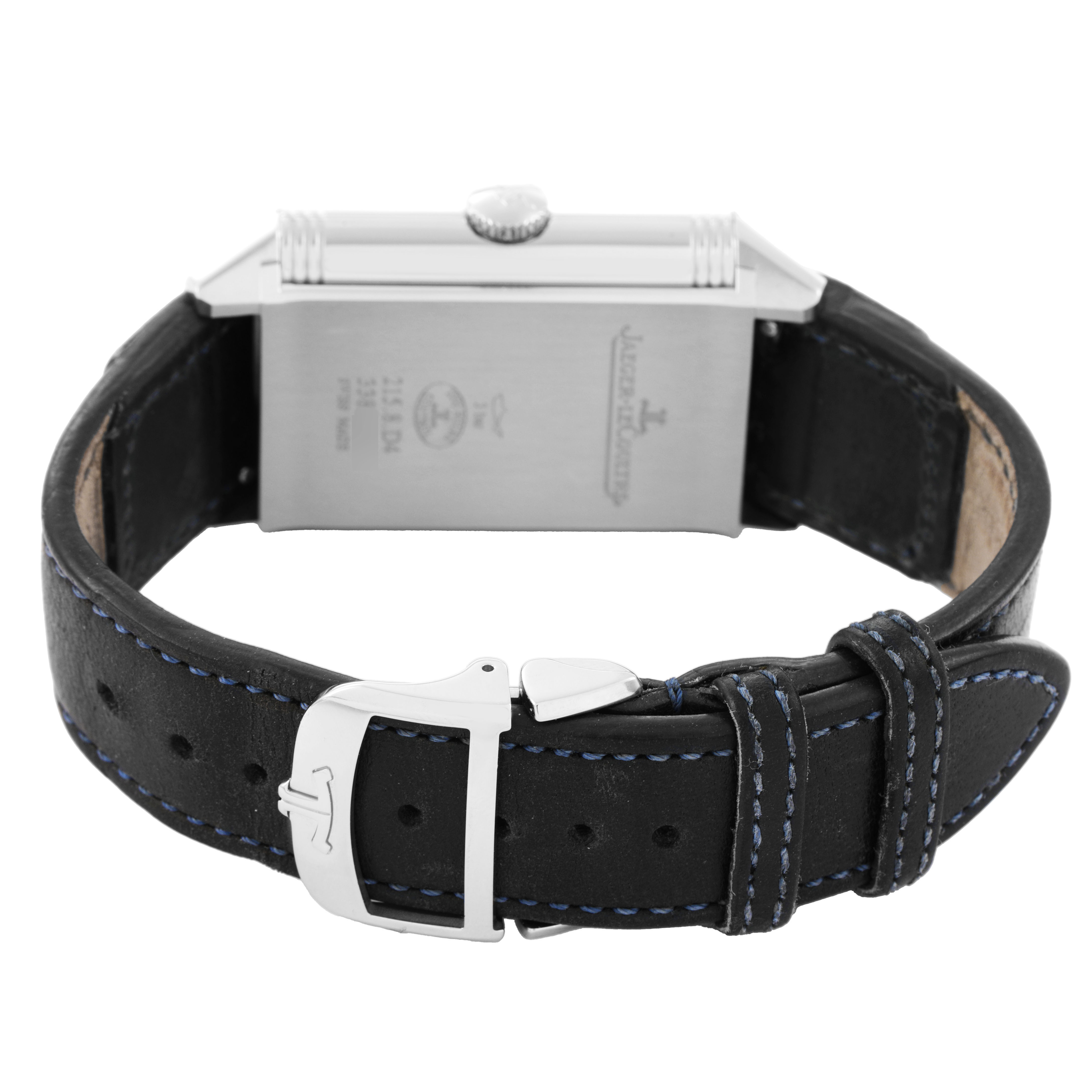 The Jaeger-LeCoultre Reverso watch is shown from the back, highlighting the case, buckle, and leather strap with blue stitching.