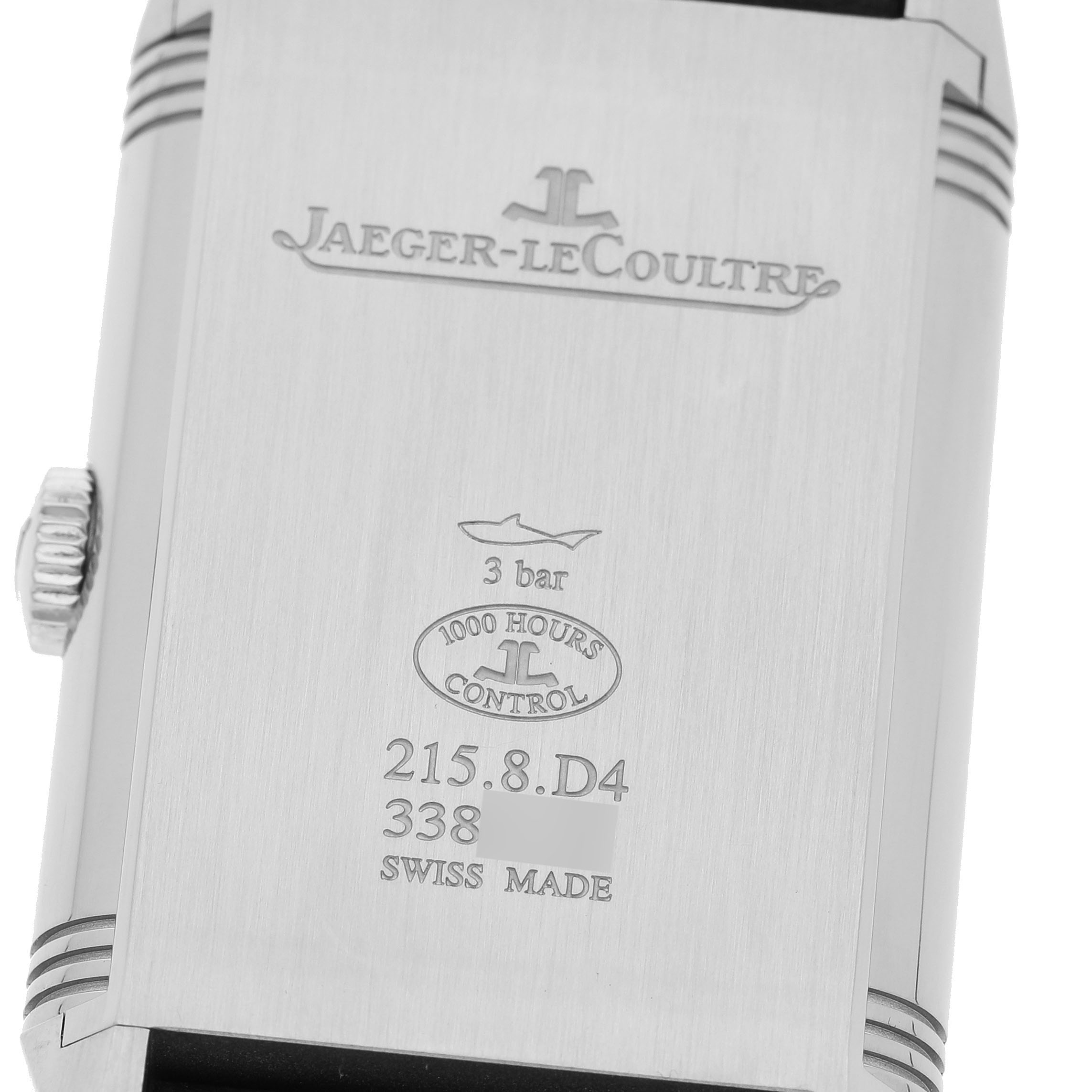 The image shows the back of a Jaeger-LeCoultre Reverso watch, displaying engravings and the crown on the side.