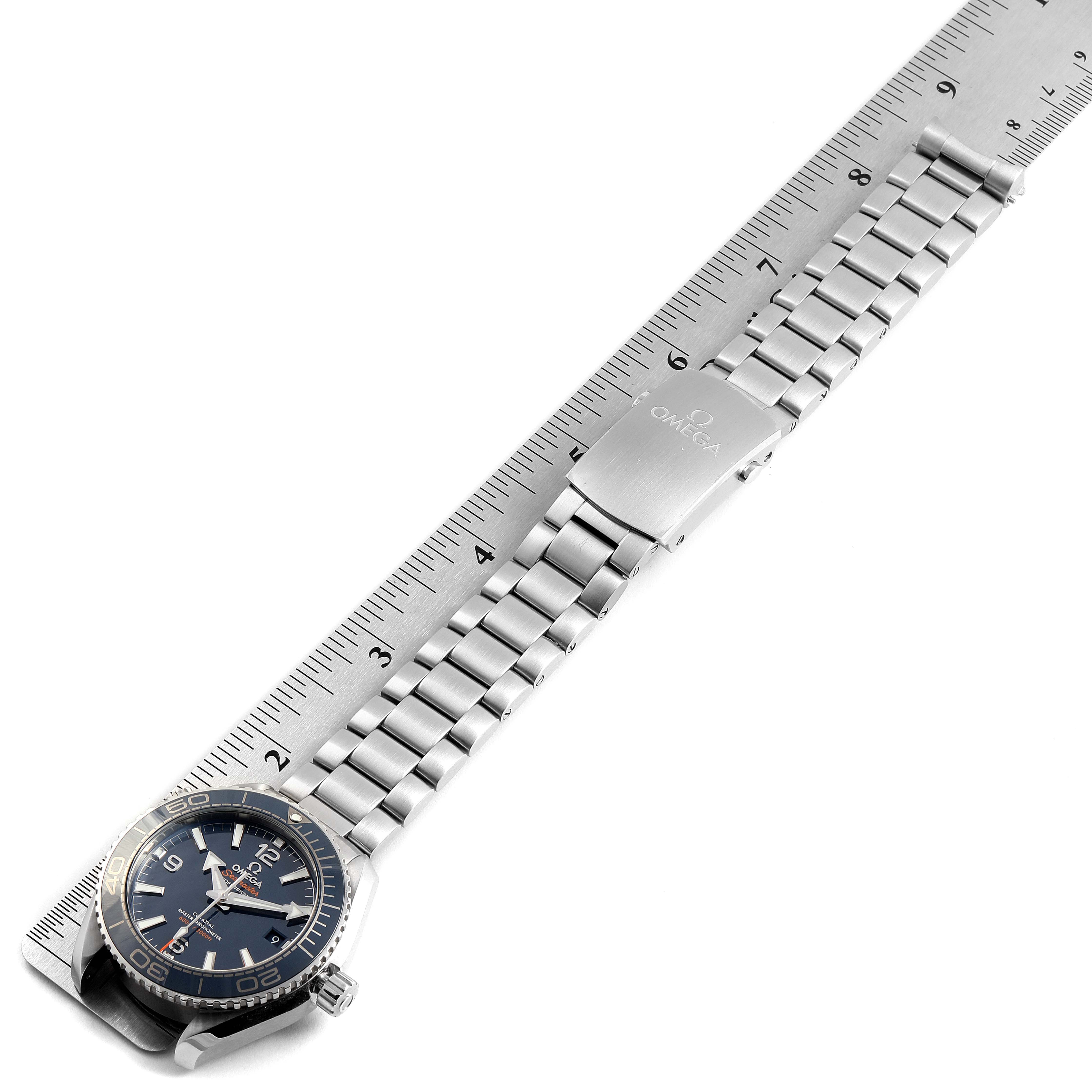 The image shows an Omega Planet Ocean 215.30.40.20.03.001 Men
s Stainless Steel Blue Dial 215.30.40.20.03.001 Men
s Stainless Steel Blue Dial watch laid flat with a ruler for scale, displaying its face, bracelet, and clasp.