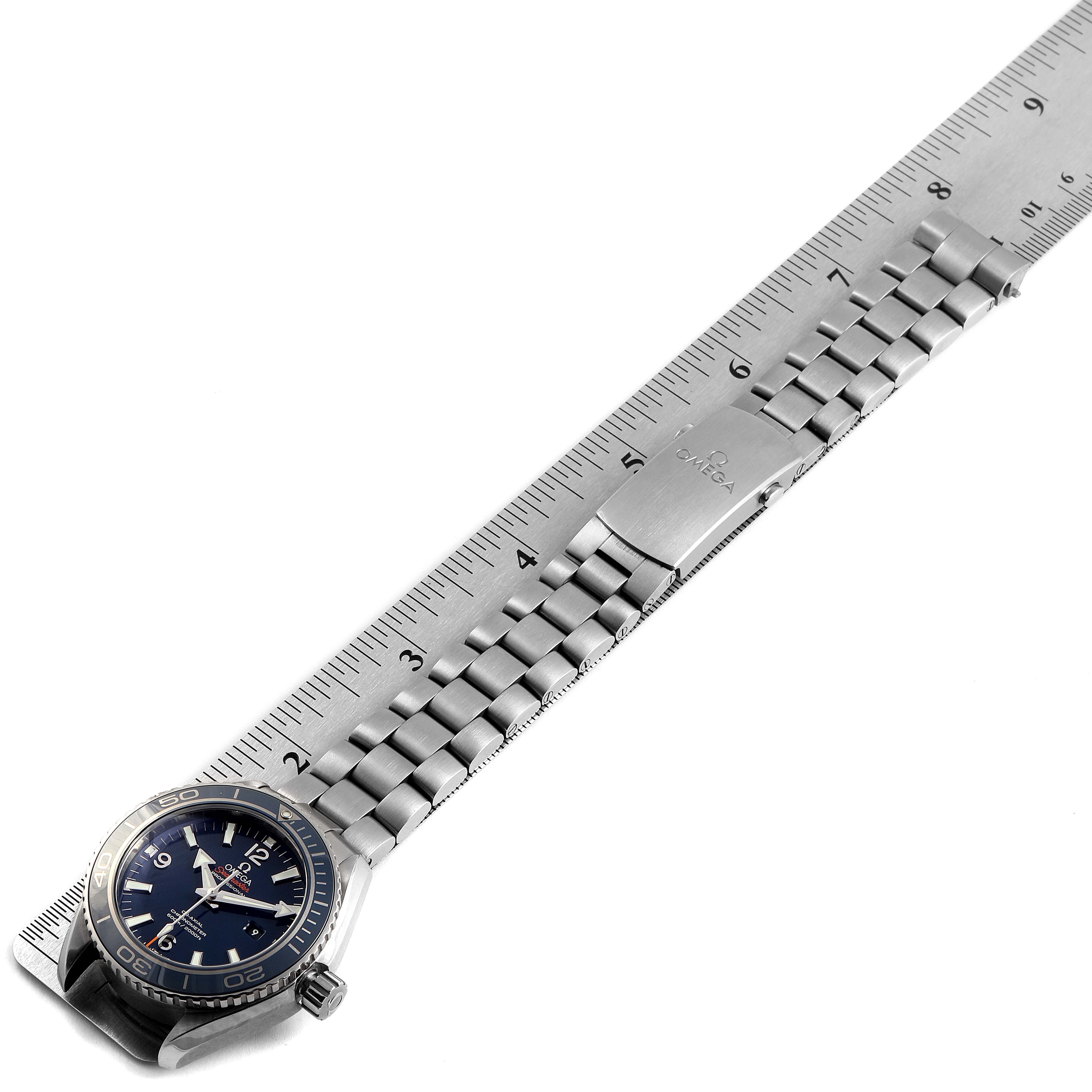 The Omega Planet Ocean 232.90.38.20.03.001 Men's Titanium Blue Dial 232.90.38.20.03.001 Men's Titanium Blue Dial watch is shown from an overhead angle alongside a metal ruler.