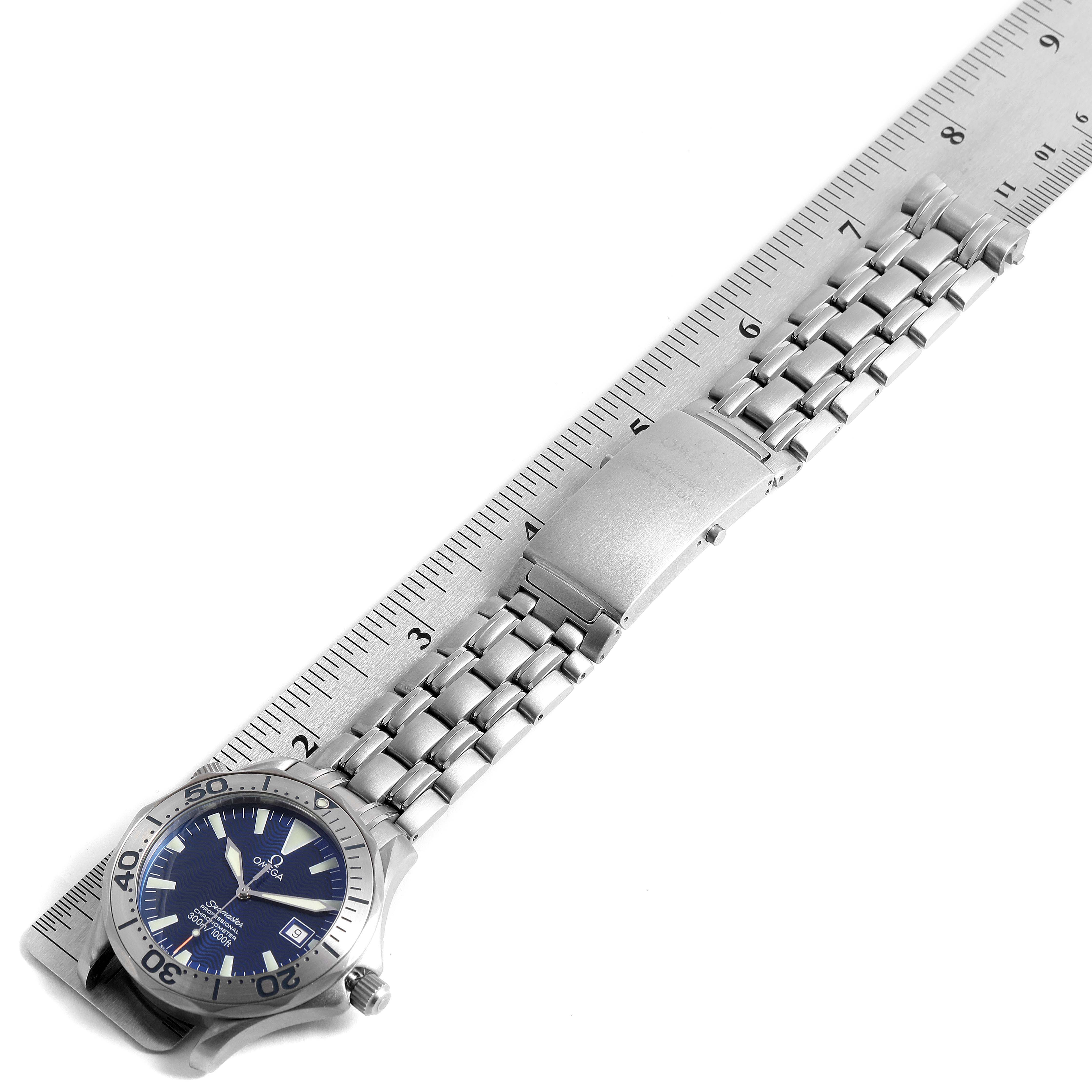 The Omega Seamaster 2231.80.00 Men
s Titanium Blue Dial 2231.80.00 Men
s Titanium Blue Dial watch is shown from a top-down angle, highlighting the face, bezel, and metal bracelet alongside a ruler.