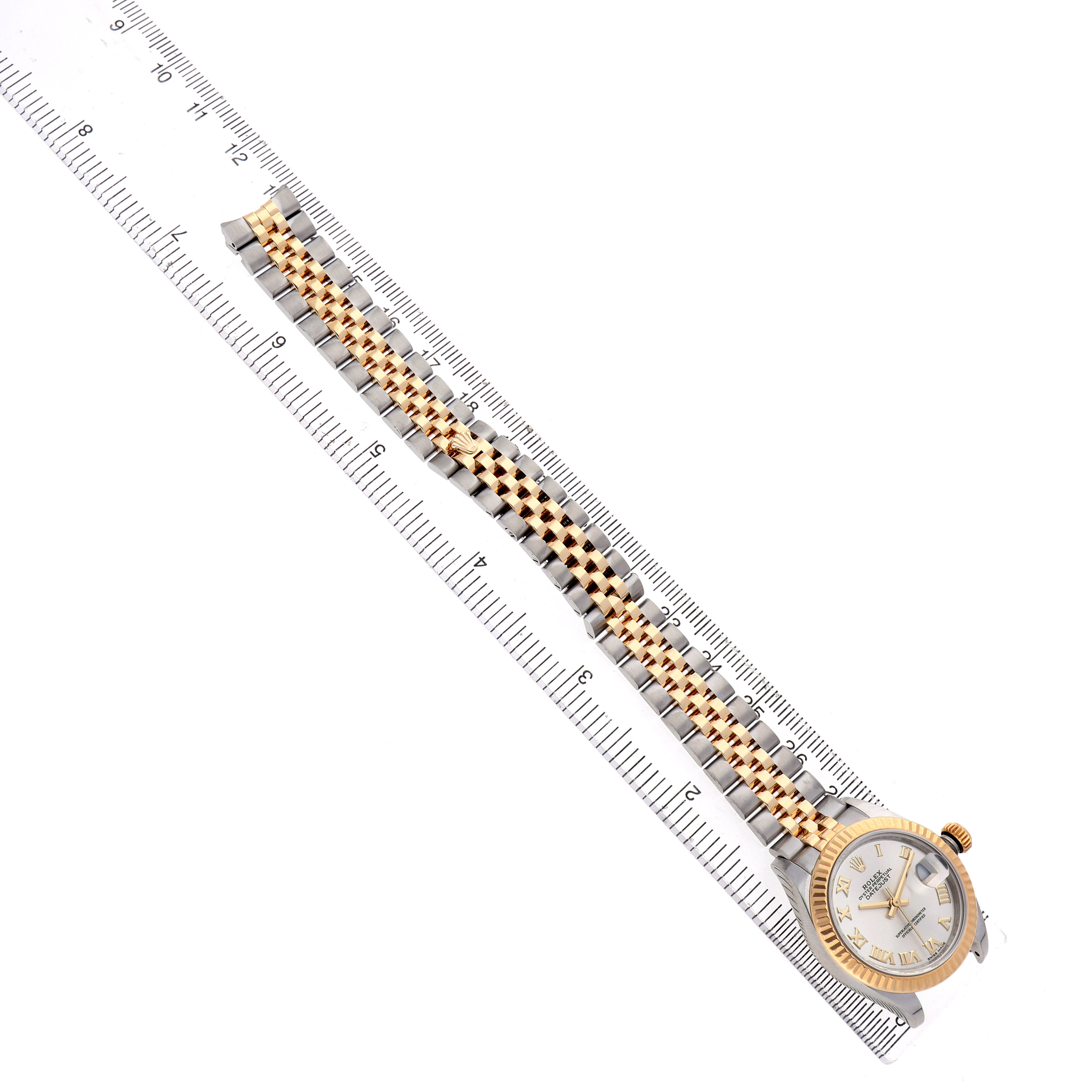 The Rolex Datejust 279173 Women's Steel and Gold (two tone) Silver Dial watch is shown from a top view with its two-tone bracelet and case beside a ruler.