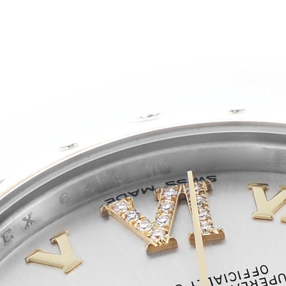The image shows a close-up of the dial and bezel of a Rolex Mid-Size 178343 Women
s Steel and Gold (two tone) Silver Dial watch, highlighting the Roman numeral VI with diamond accents.