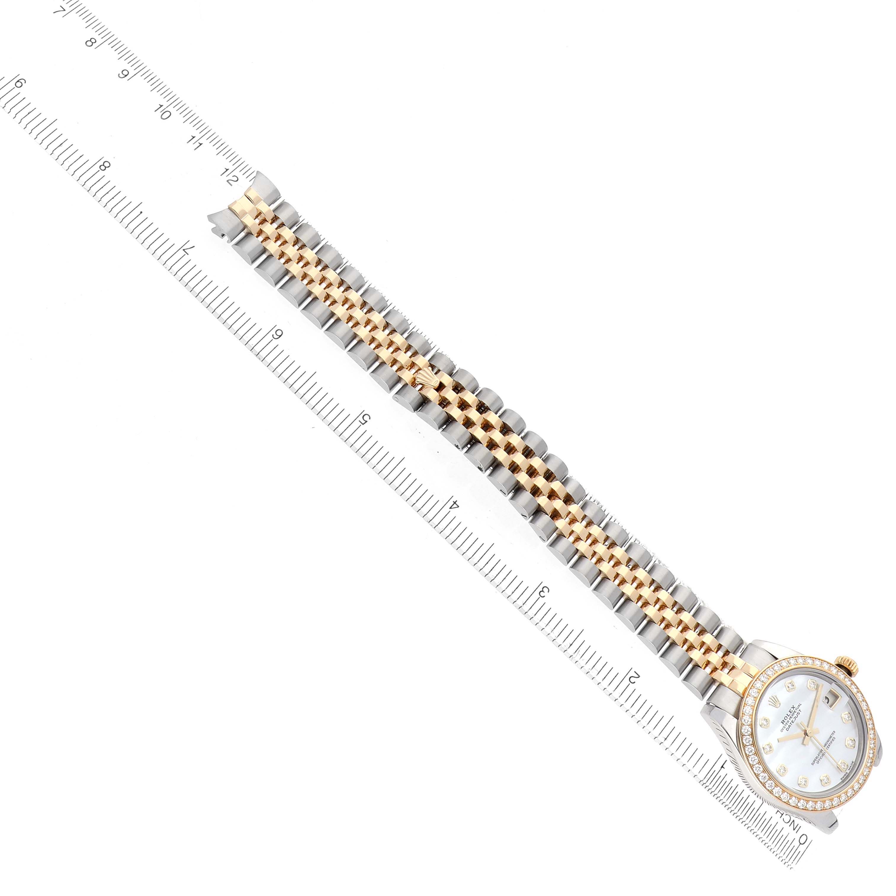 The Rolex Mid-Size 178383 Women
s Steel and Gold (two tone) Mother of Pearl Dial watch is shown from a top-down angle, displaying the full bracelet and face, alongside a ruler for scale.