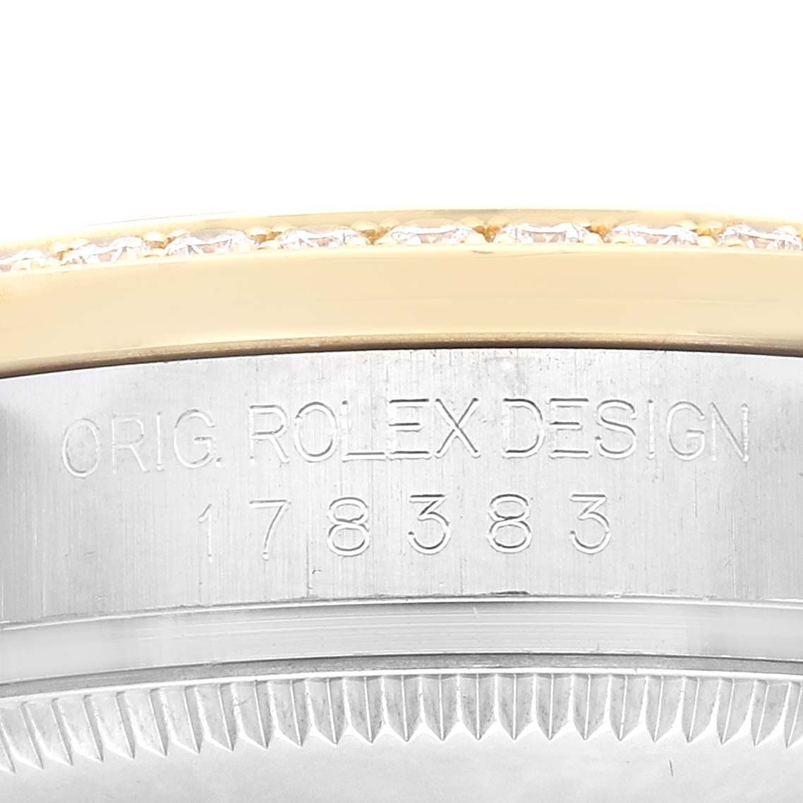 The image shows the engraved side of the bezel and casing of a Rolex Mid-Size 178383 Women
s Steel and Gold (two tone) Black Dial model, highlighting the serial number and design engraving.
