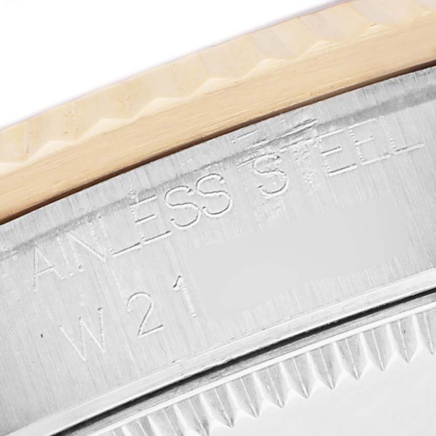 The image shows a close-up of the case edge and bezel of a Rolex Mid-Size 68273 Women
s Steel and Gold (two tone) Black Dial watch, highlighting the "Stainless Steel" engraving.