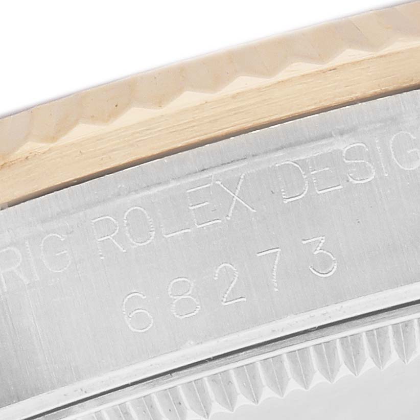 The image shows a close-up of the edge of a Rolex Mid-Size 68273 Women
s Steel and Gold (two tone) Black Dial watch case, highlighting the engraved model number 68273 and part of the bezel.