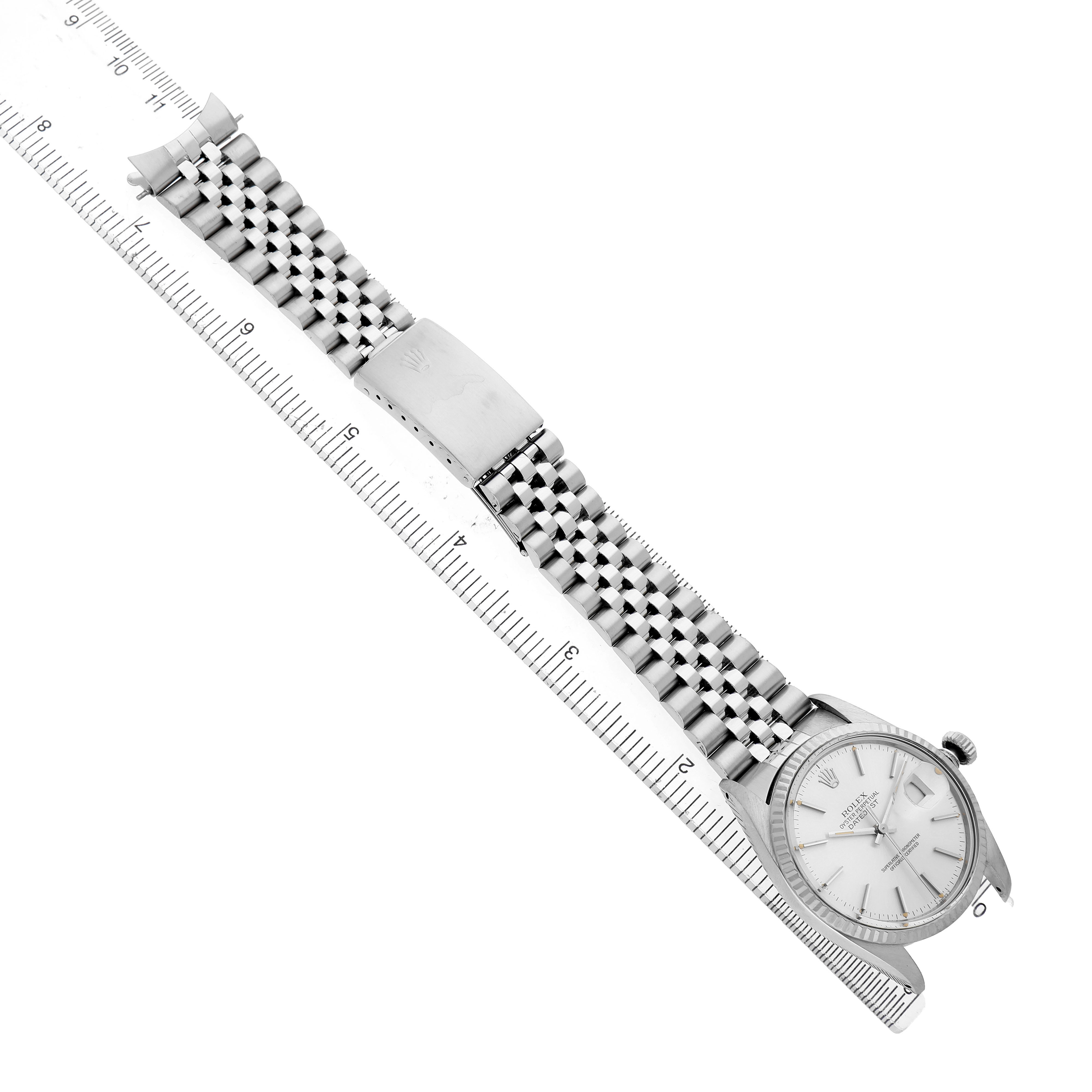 The Rolex Datejust 16014 Men's Stainless Steel Silver Dial watch is shown diagonally, displaying the face, case, and bracelet alongside a ruler for scale.