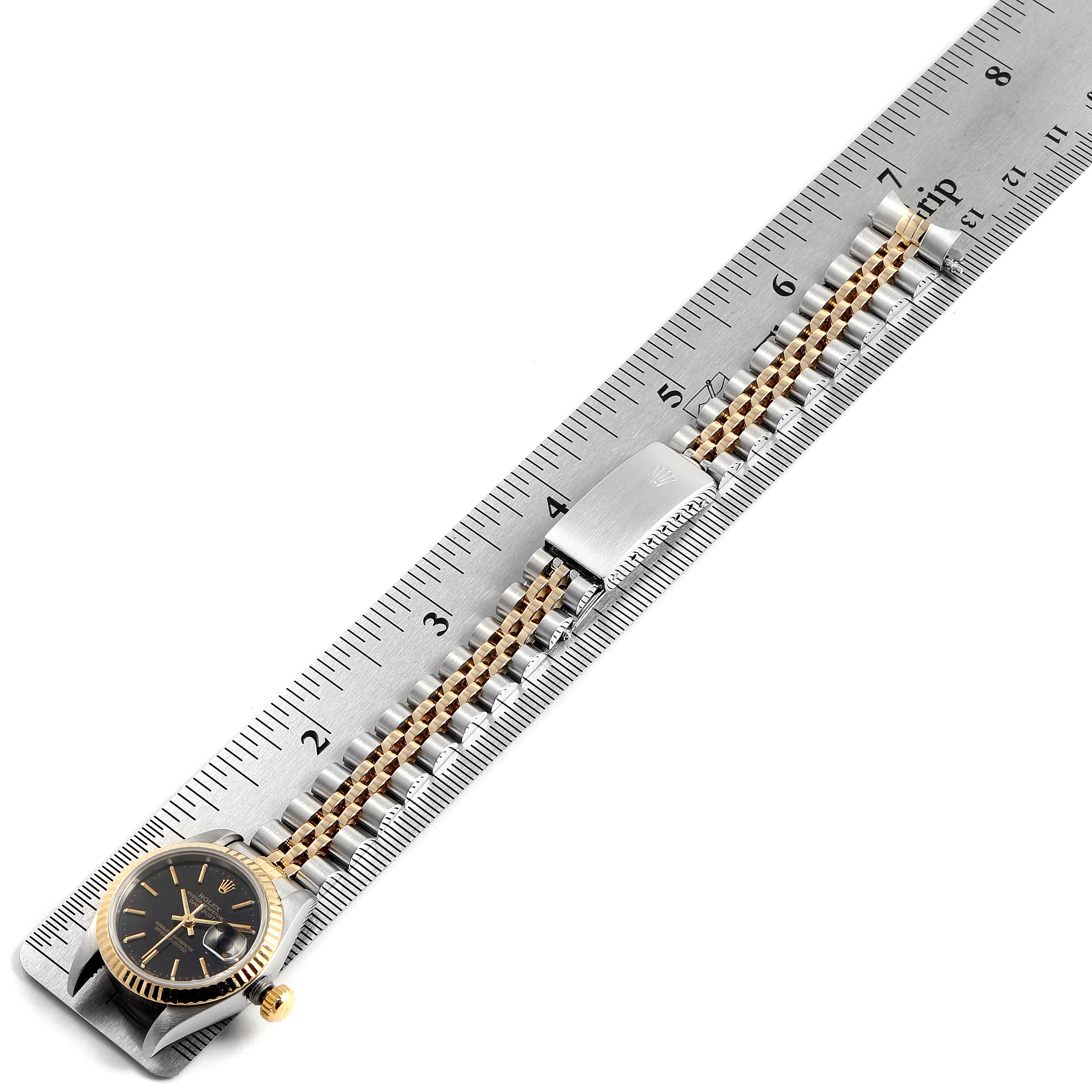 The image shows a Rolex Datejust 69173 Women's Steel and Gold (two tone) Black Dial 69173 Women's Steel and Gold (two tone) Black Dial watch laid flat with its case and bracelet next to a ruler for measurement.
