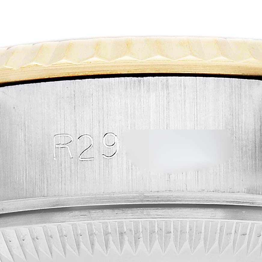 The image shows a close-up of the Rolex Datejust 69173 Women
s Steel and Gold (two tone) Champagne Dial model case, focusing on the engraved serial number and the fluted bezel edge.