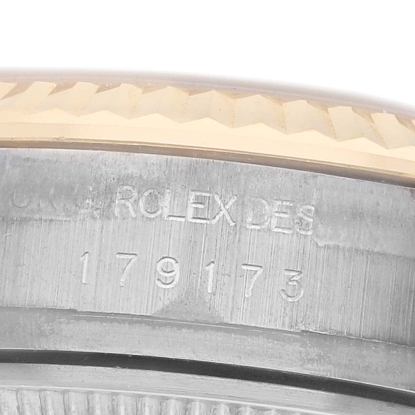 The image shows a close-up of the side engraving and bezel detailing on a Rolex Datejust 179173 Women
s Steel and Gold (two tone) Champagne Dial watch.